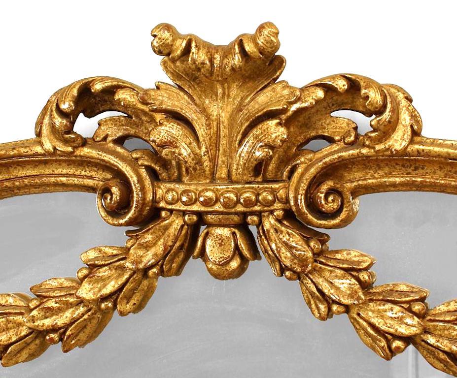 French Louis XVI style (modern) gilt framed wall mirror with carved floral trim and rounded top with swags and crest.
 