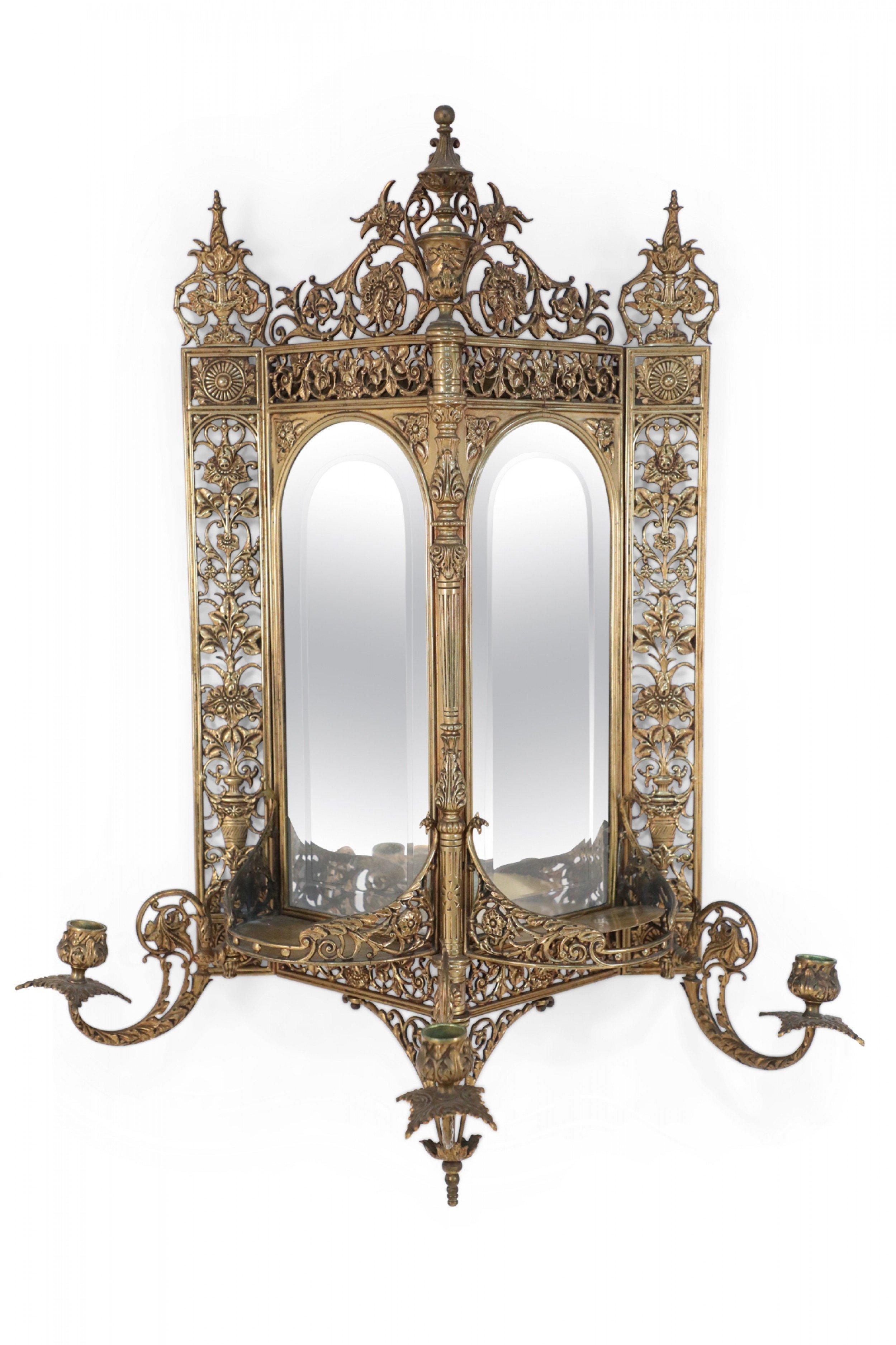 French Victorian style brass triangular wall shelf with elaborate gilt filigree & 2 mirrored sides having a beveled edge with three removable candle arms.
 