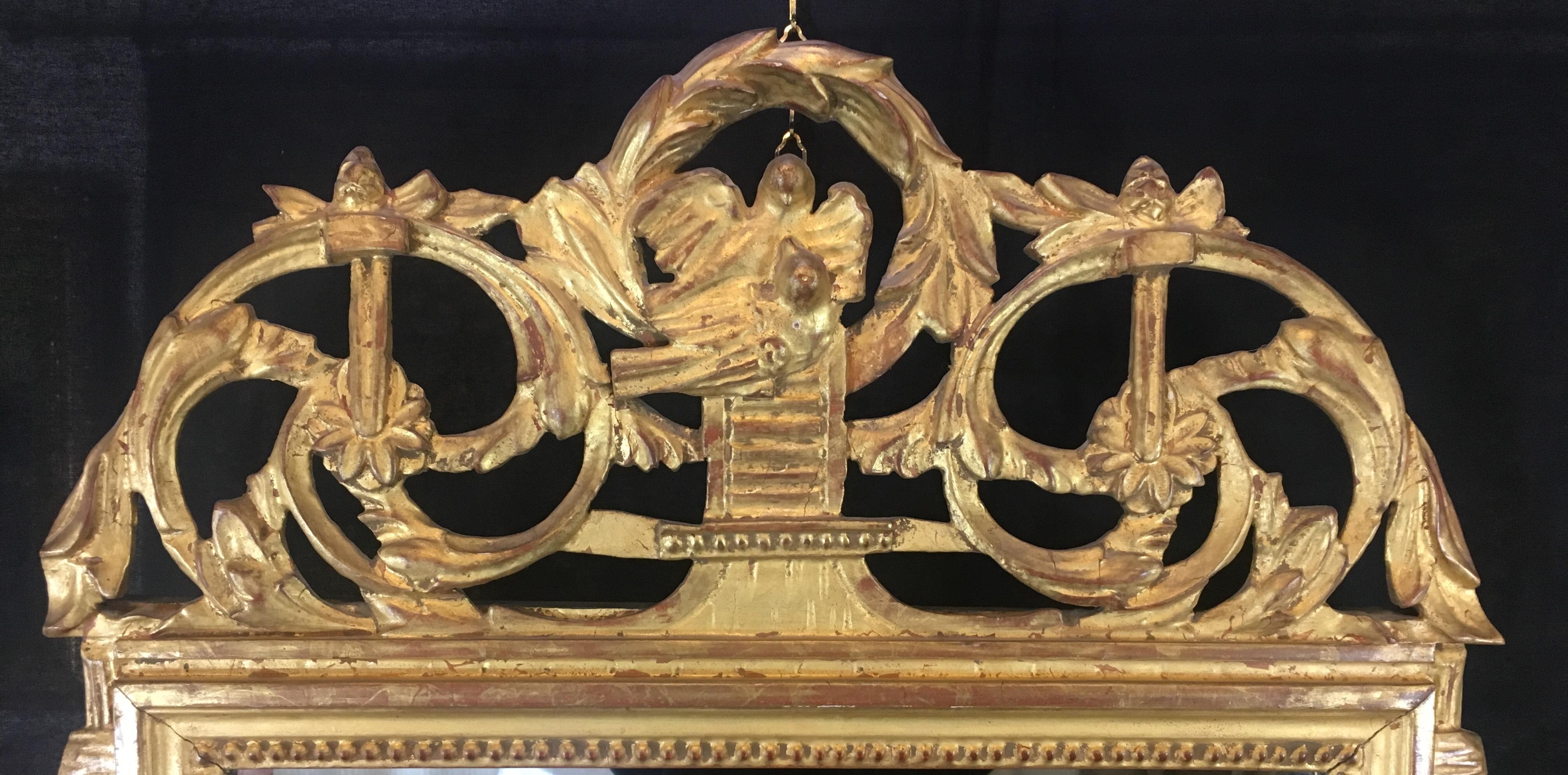 French Louis XVI style gilt wall mirror with beautiful hand carved details and wreath pediment top.
 
This mirror is very decorative and would enhance any wall or mantle in a space you deem appropriate.