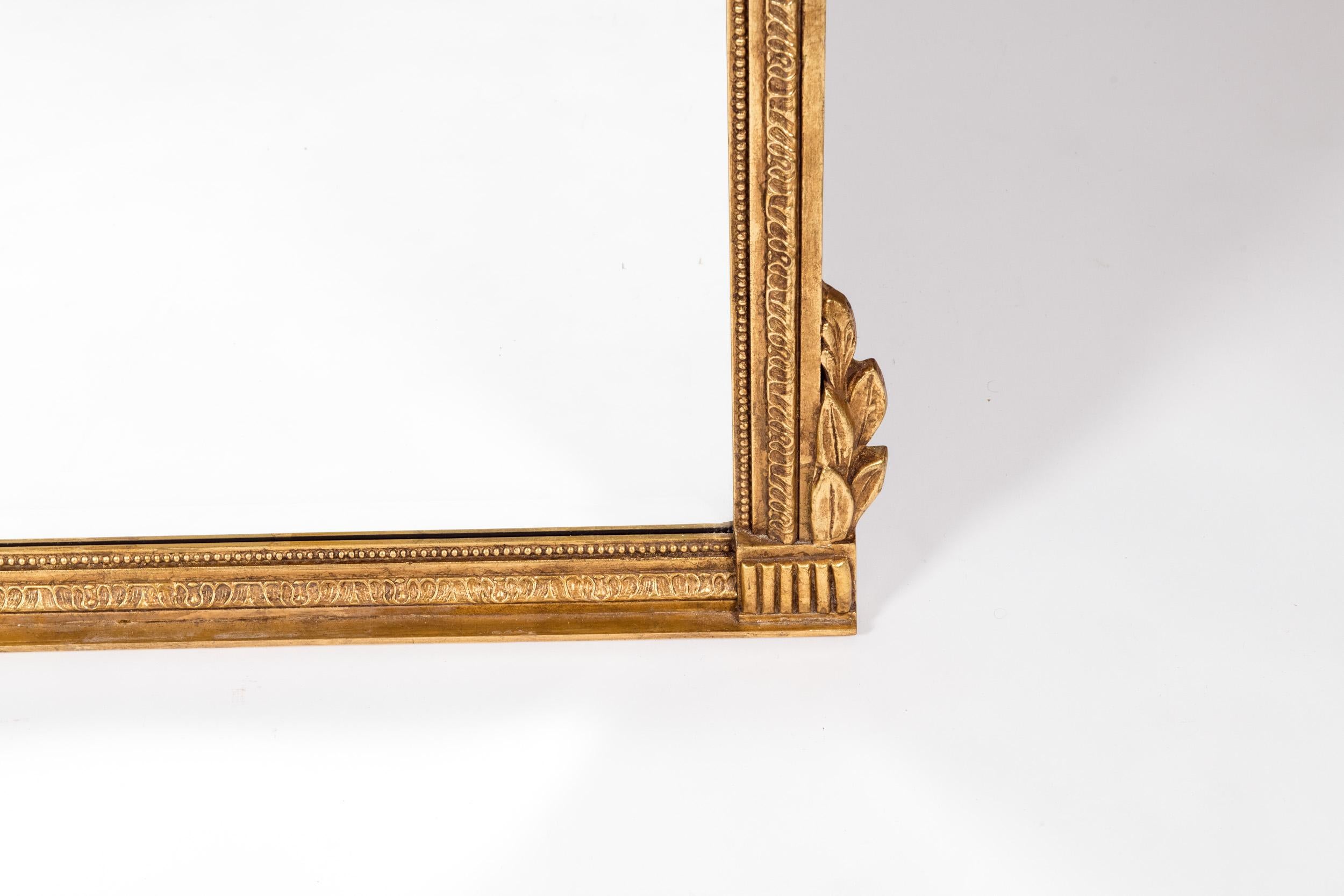 French Louis XVI style gilt wood beveled hanging wall mirror. The beveled hanging mirror is in excellent vintage condition. Minor wear consistent with use / age. The mirror measure about 46 inches high x 40 inches wide.
