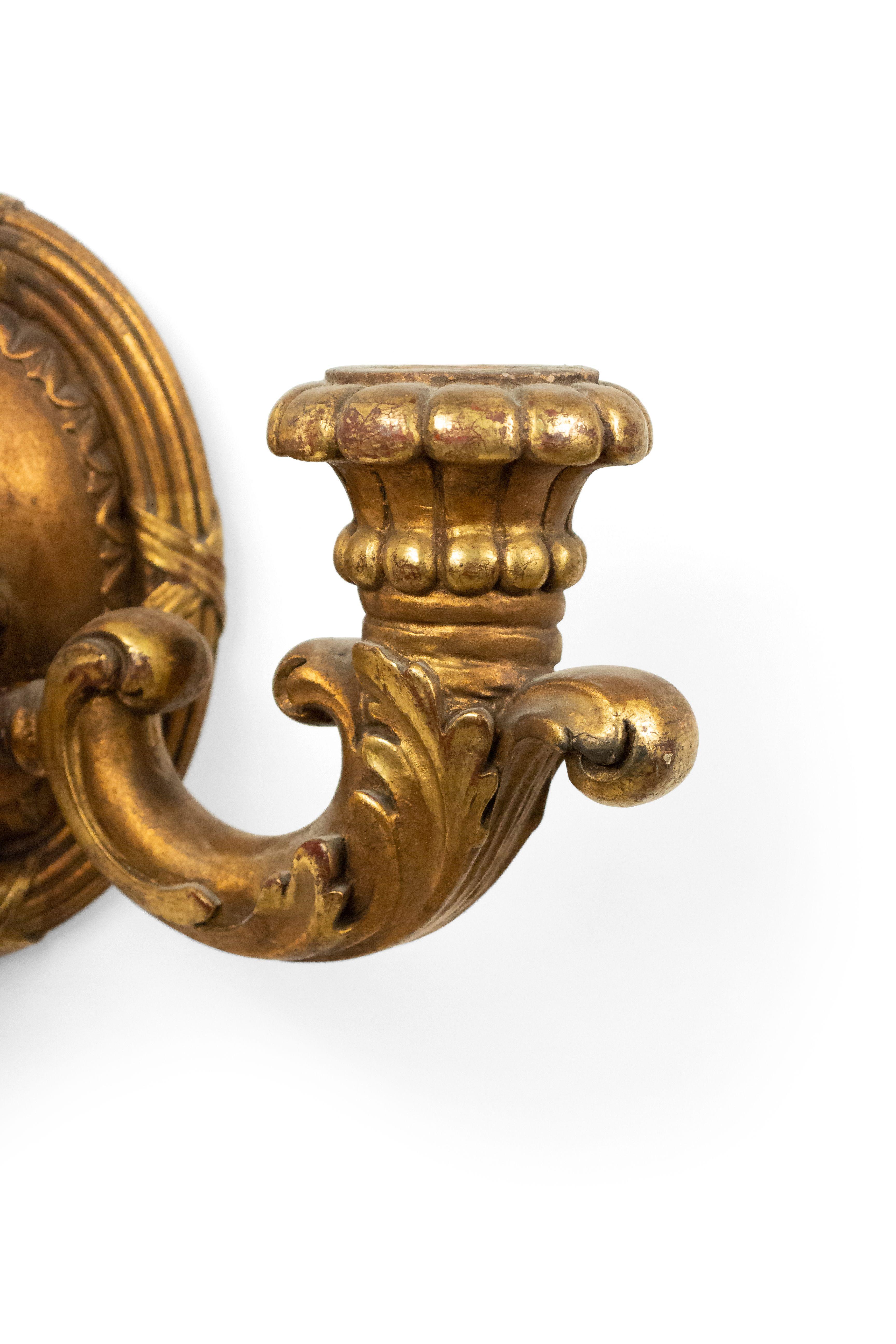 Pair of French Louis XVI style giltwood 2-arm wall sconces with fluted oval back, (19th-20th century).