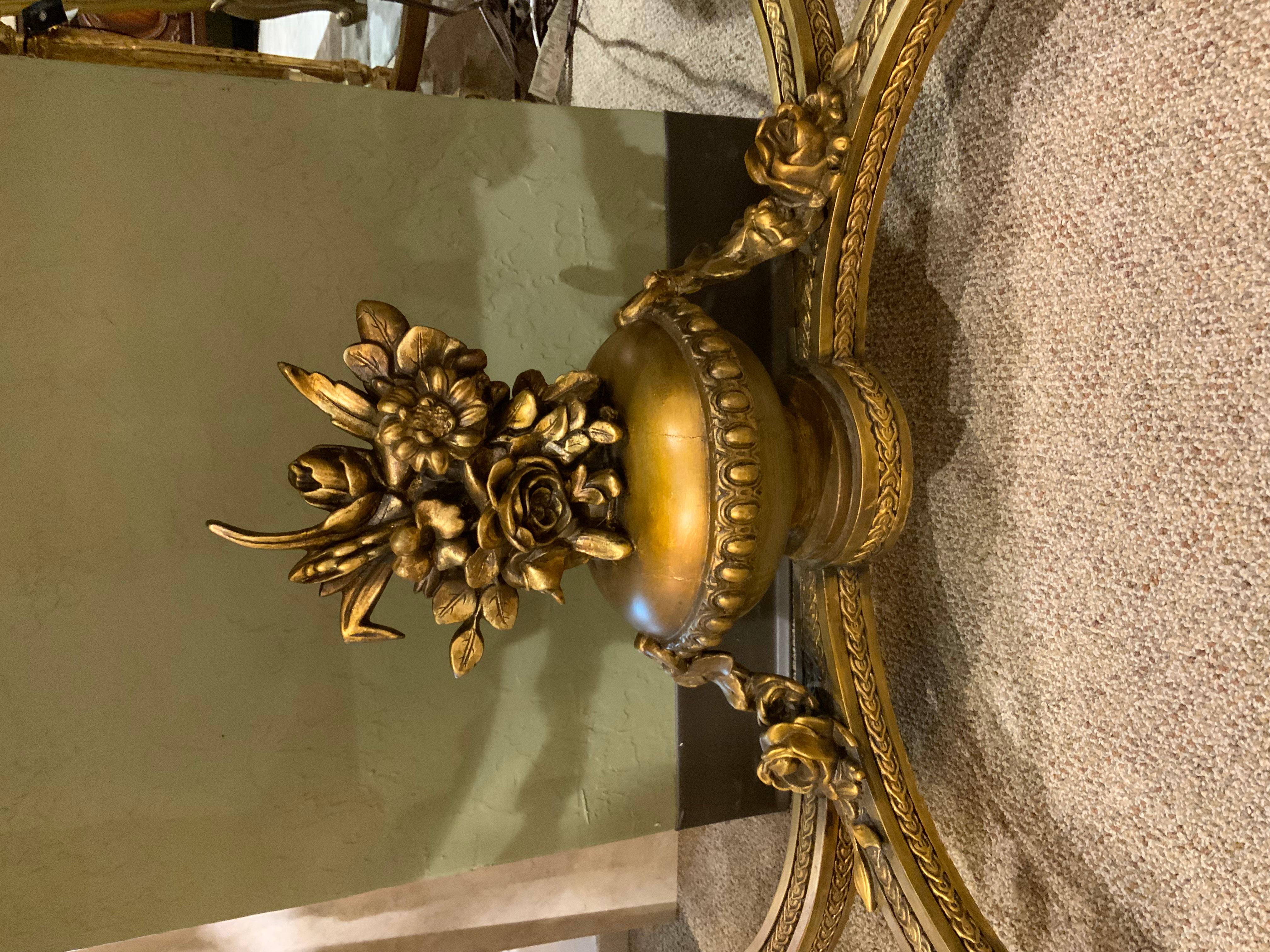 Giltwood that is hand carved with an oval shaped front, standing on four legs that are reeded
And connected by a carved stretcher that is connected with an urn at the center.
The marble is in white, gray and cream hues. The center front has a bow