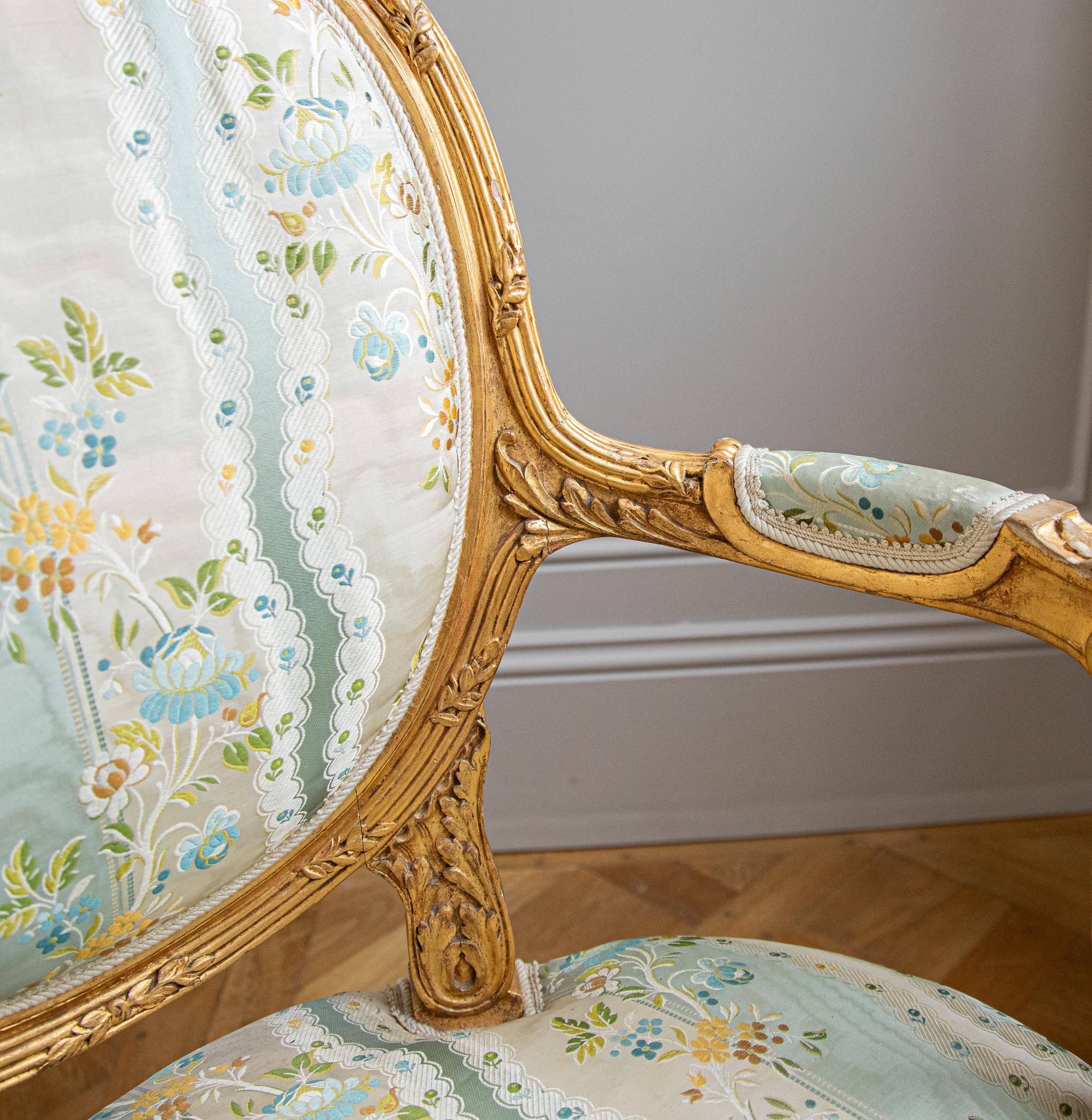 Circa late 1800's, a Louis XVI Style, Medalion back armchair & matching foot stool from France. This two piece set has a fine quality of carving that makes up its LXVI details, which include: ribbon work, stylised acanthus leaf, rosaces, fluted legs