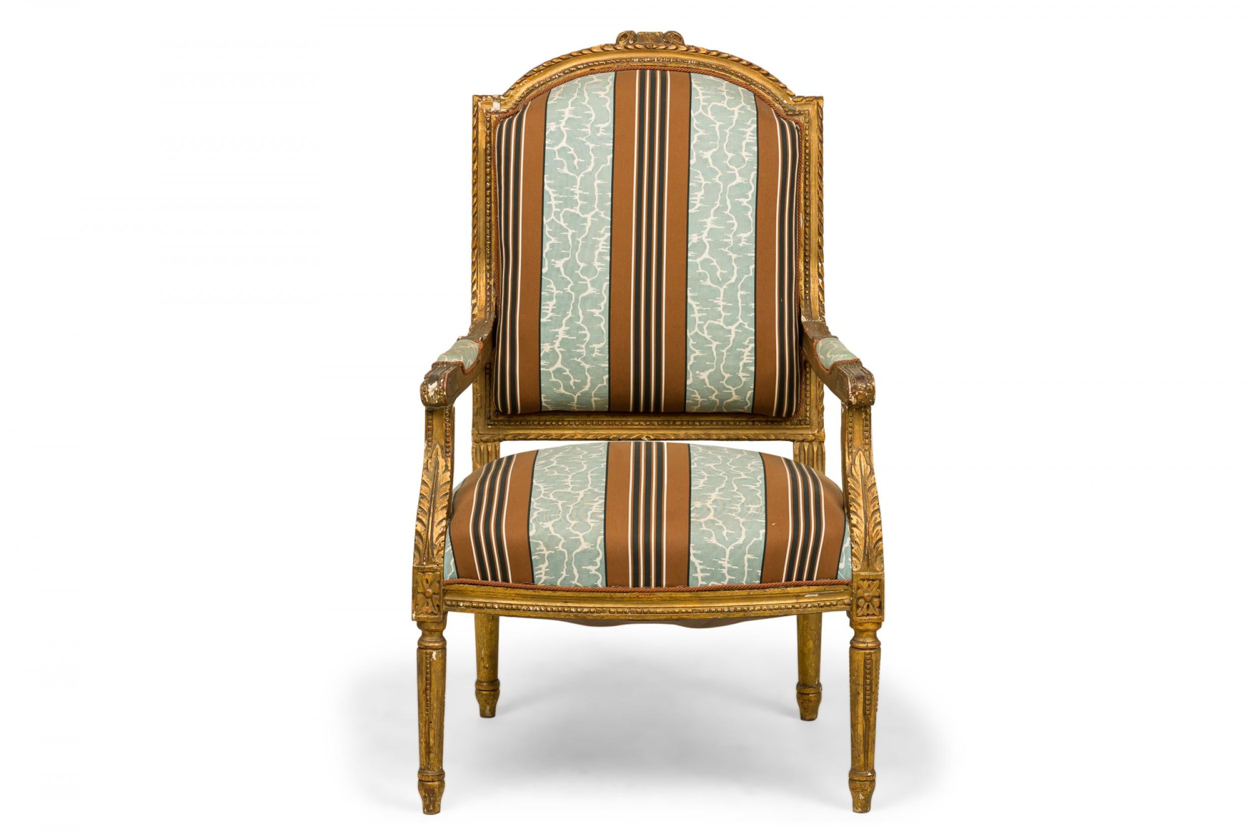 French Louis XVI-style (20th Century) armchairs with carved giltwood frames and seats and backs upholstered in a broad striped light blue, rust red, and black fabric. (PRICED AS PAIR).