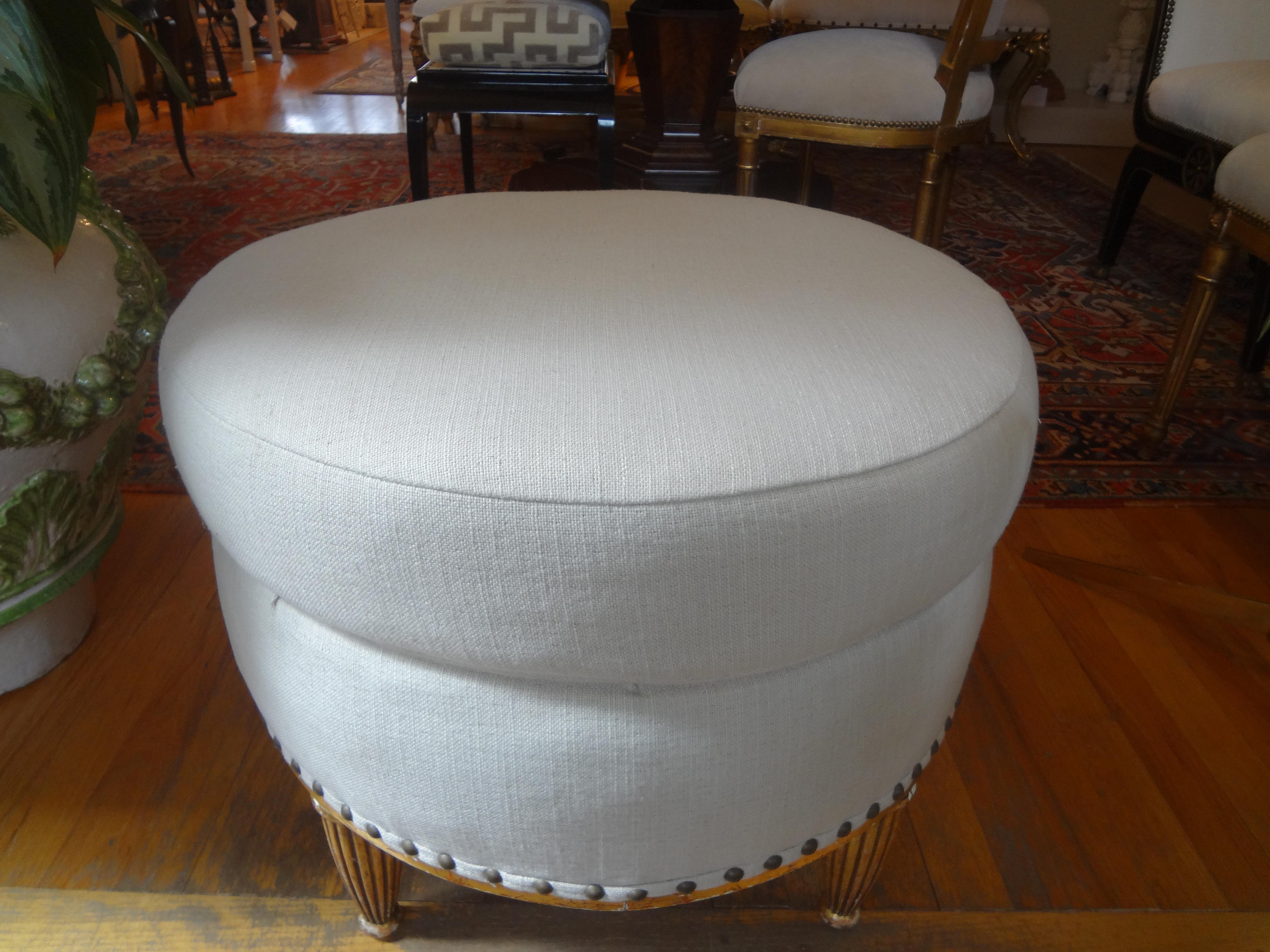 Stunning antique French Louis XVI style giltwood bench, ottoman, stool or pouf with fluted legs. This beautiful French gilt wood pouf has been professionally upholstered in cream linen with spaced brass nailhead detail.