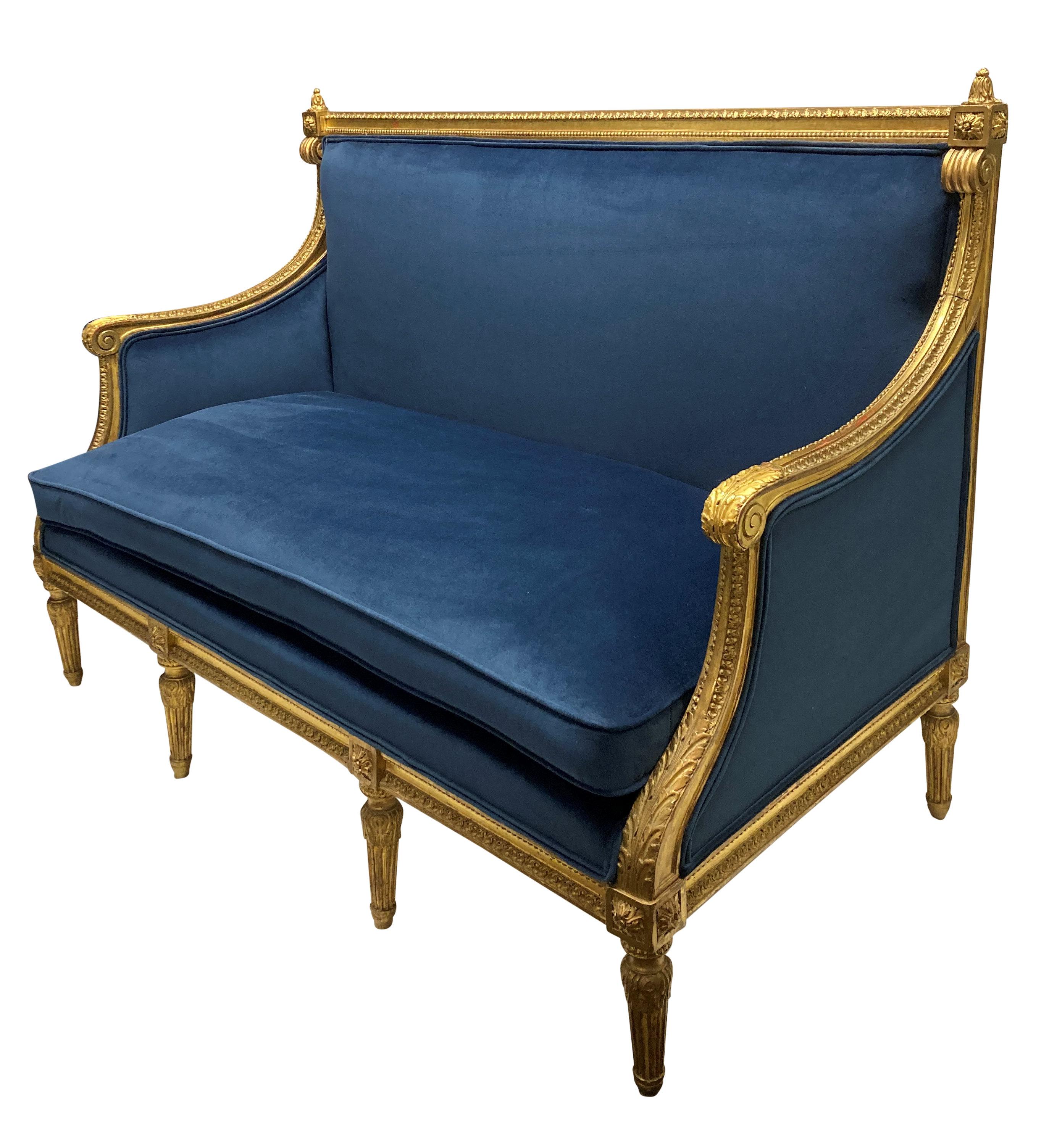 A fine French Louis XVI style carved giltwood settee, water gilded and newly upholstered in blue velvet.