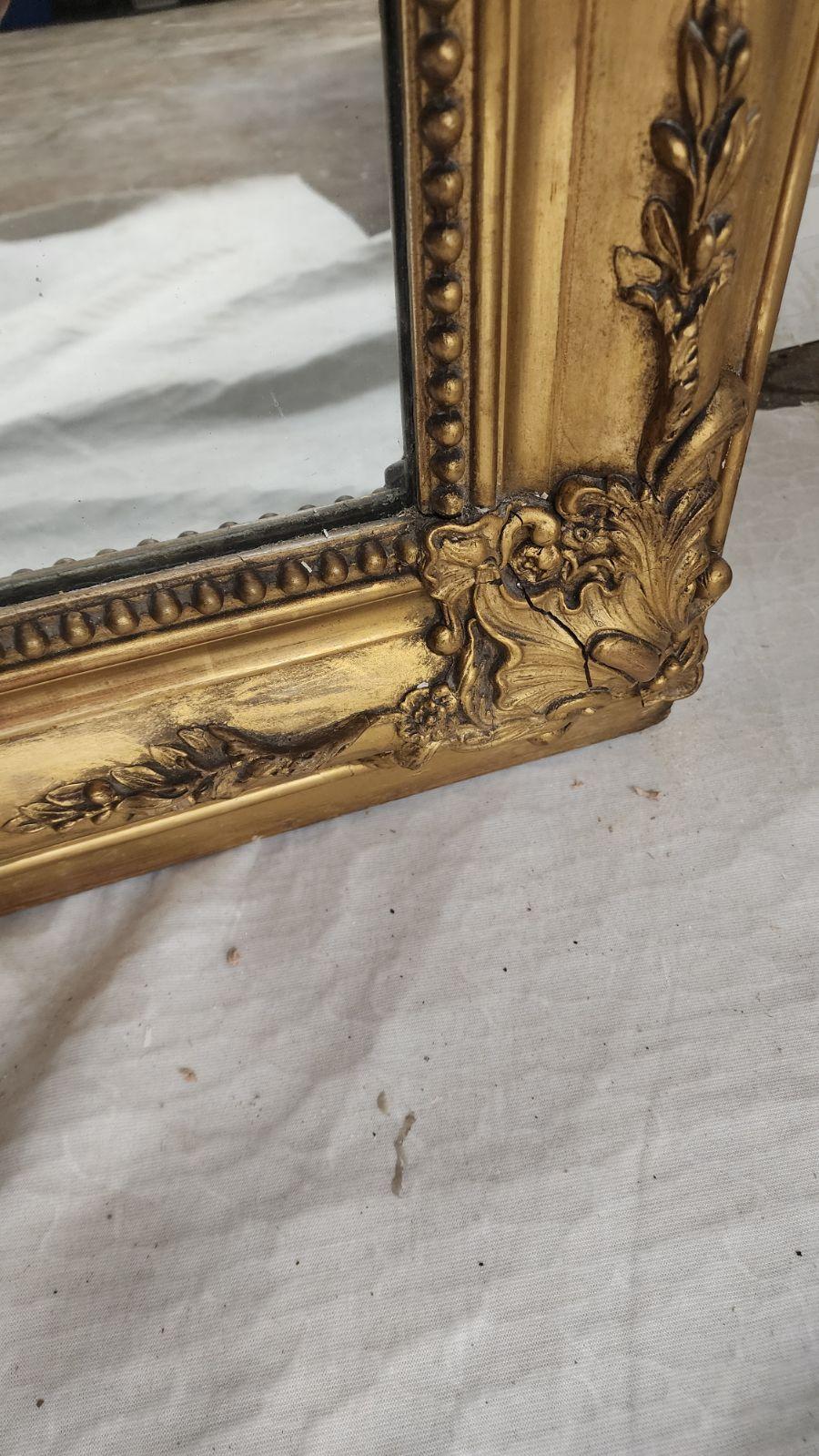 Miroir mural en bois doré de style Louis XV français du XIXe siècle, avec une crête rocaille ajourée, un cadre gaufré fleuri et une plaque de miroir plate encastrée.