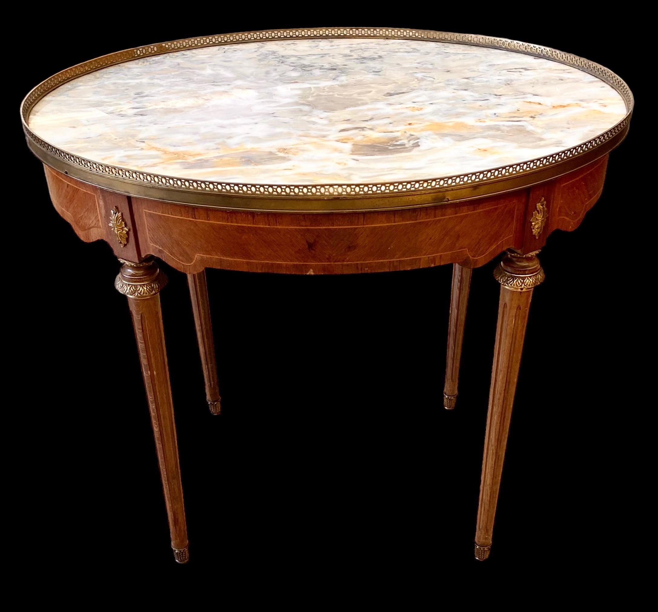 French Louis XVI Style Inlaid Carved Walnut
Marble Top Bouillotte Table, 20th c., the oval brass galleried white marble top over a wide skirt with one frieze drawer, on turned tapered legs with ormolu sabots. 

A 20th century Louis XVI style
