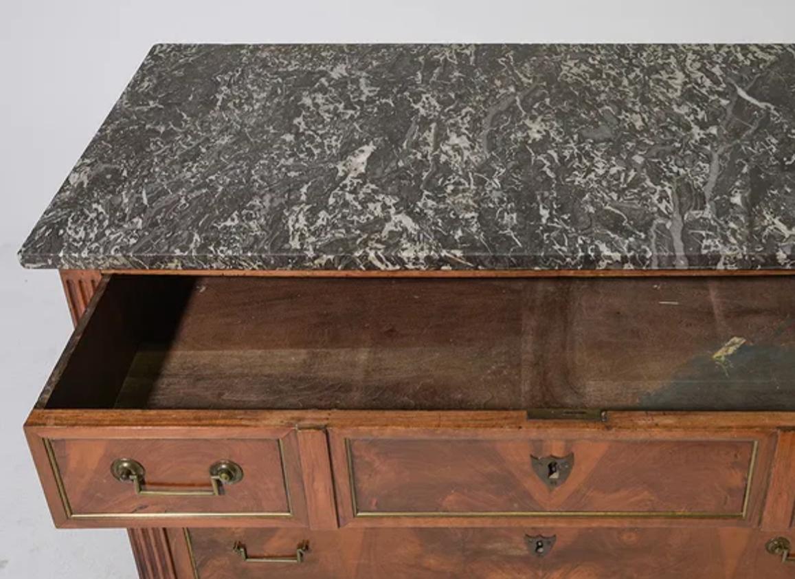 De finales del siglo XVIII, esta cómoda francesa de nogal presenta una elegante encimera de mármol de Santa Ana. Dispone de tres cajones de cola de milano adornados con tiradores tradicionales y una llamativa madera burl a juego. Apoyada sobre patas