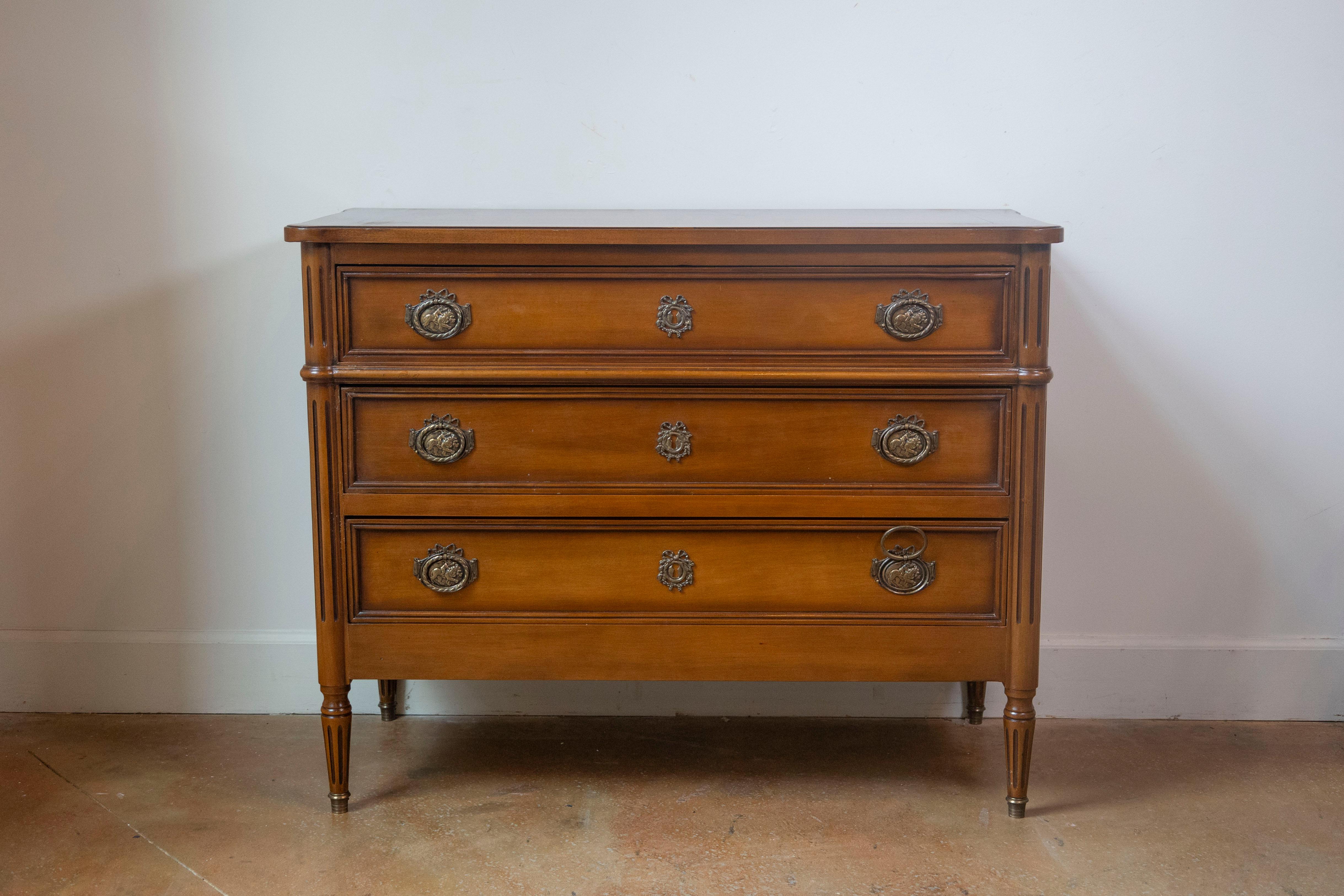 Commodo francese in stile Luigi XVI in noce chiaro del XX secolo con tre cassetti, gambe e montanti laterali scanalati, ferramenta ornata. Questo mobile francese in noce chiaro in stile Luigi XVI del XX secolo cattura con eleganza l'estetica