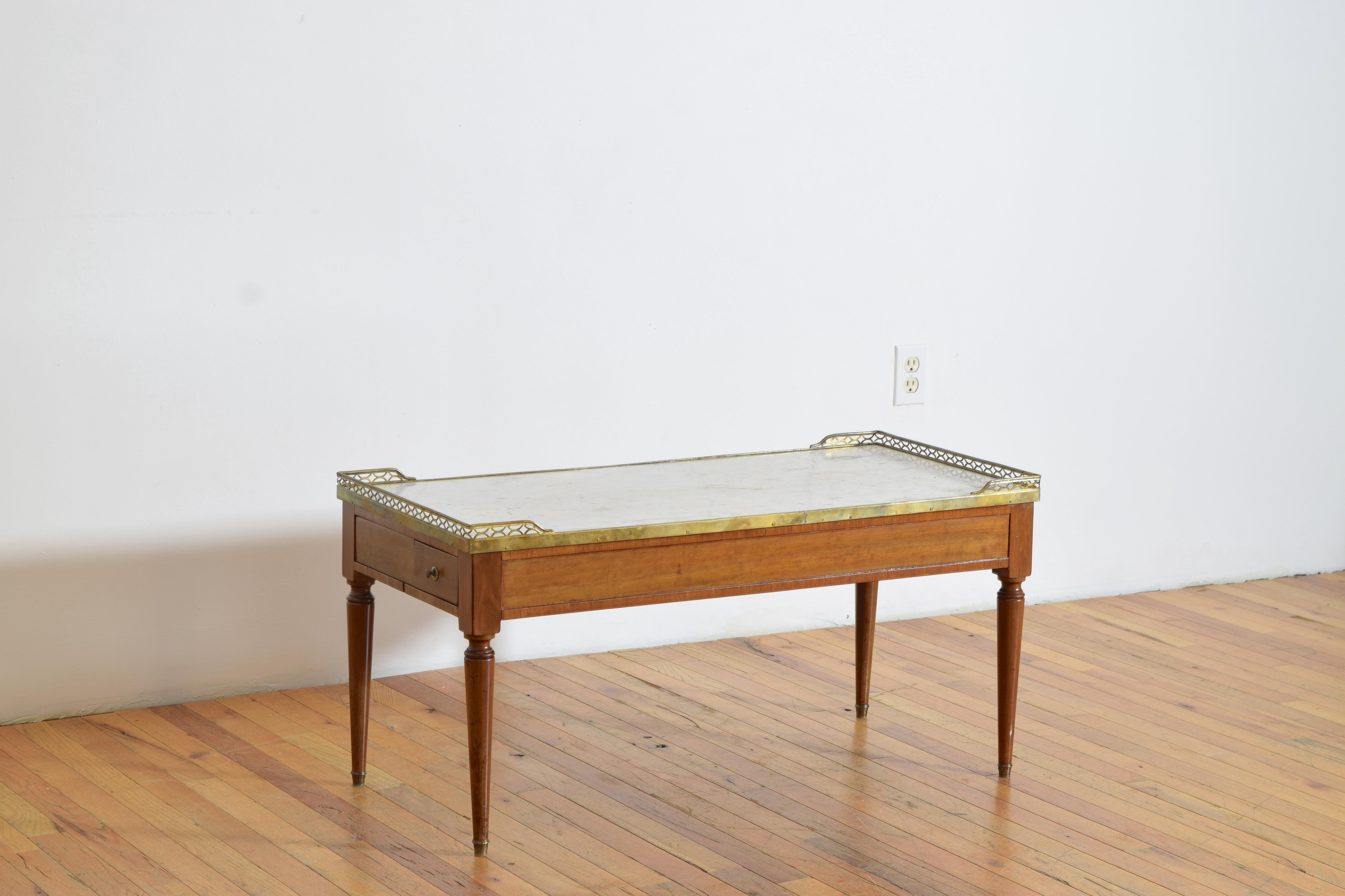 comprenant une galerie en laiton perforé surélevée au-dessus d'un plateau en marbre blanc, le marbre surmontant une base de table conforme abritant un seul tiroir, le coffret reposant sur des pieds circulaires effilés se terminant par des roulettes