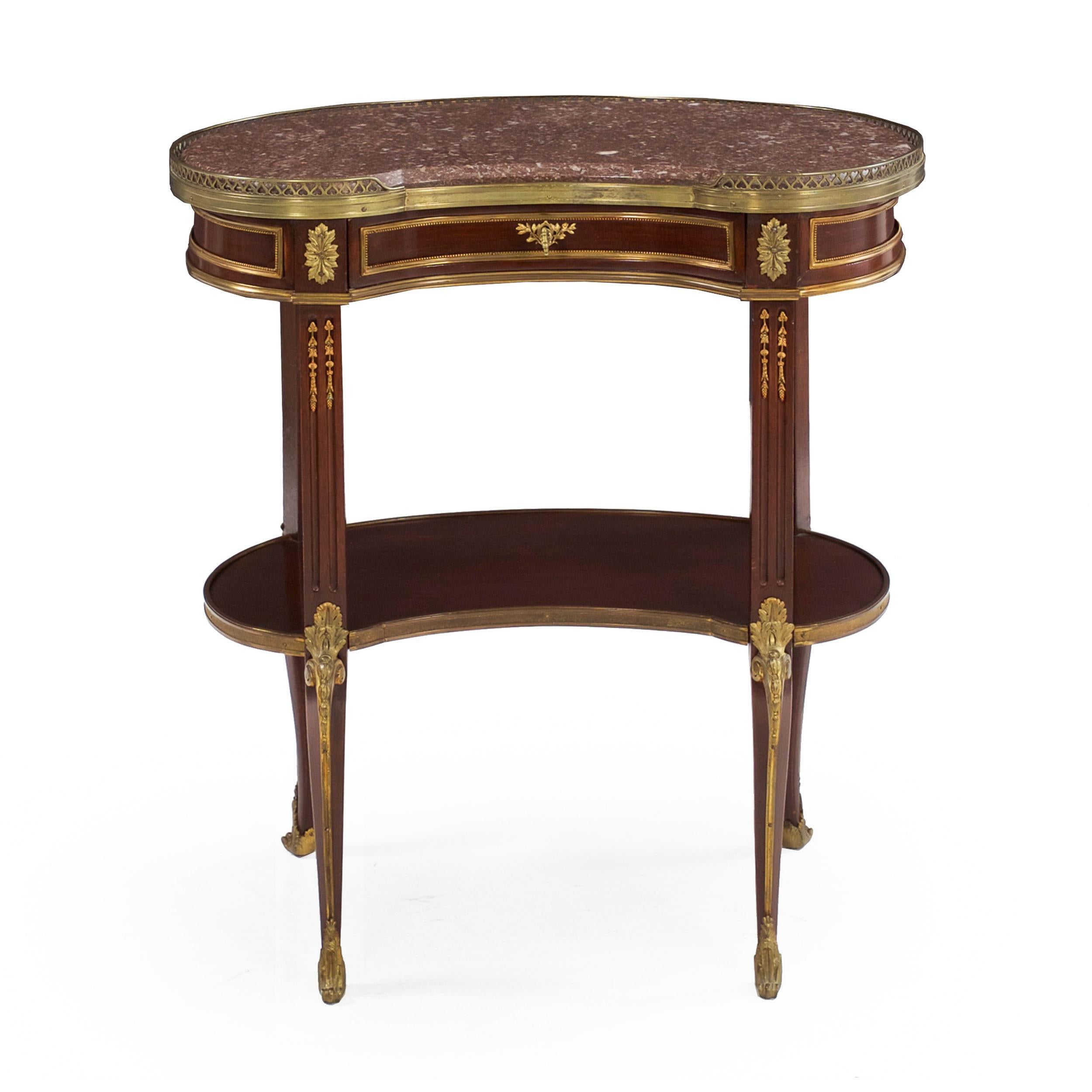 A good early 20th century accent table in the French Louis XV taste, it is crafted with an overall kidney form, the conforming marble top with a beveled edge set within a pierced brass raised gallery over a single horizontal drawer with