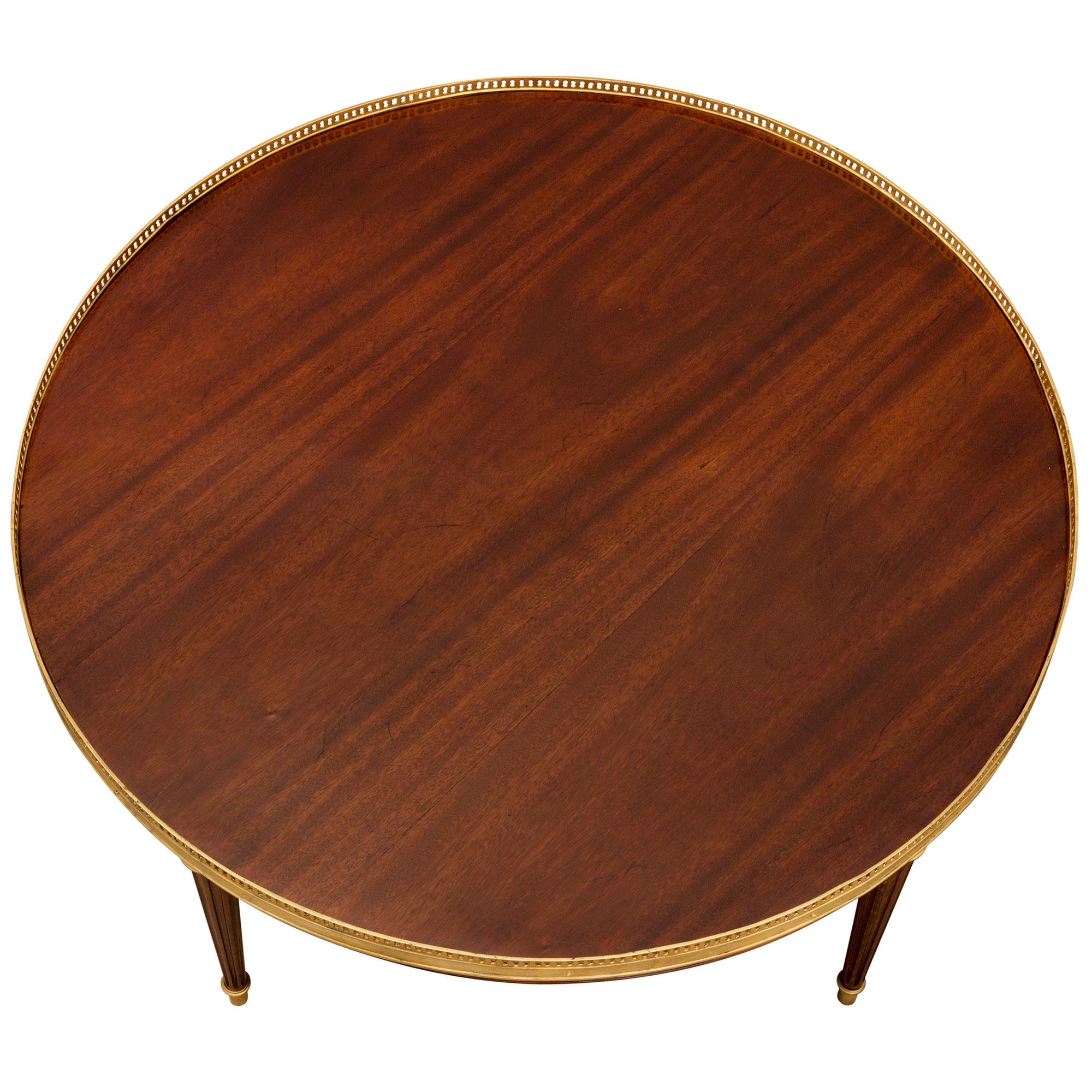 A most elegant French 19th century Louis XVI style mahogany and ormolu cocktail/coffee table. The table is raised by slender circular tapered fluted legs with fine ormolu sabots and mottled top caps. Above each leg are richly chased square ormolu