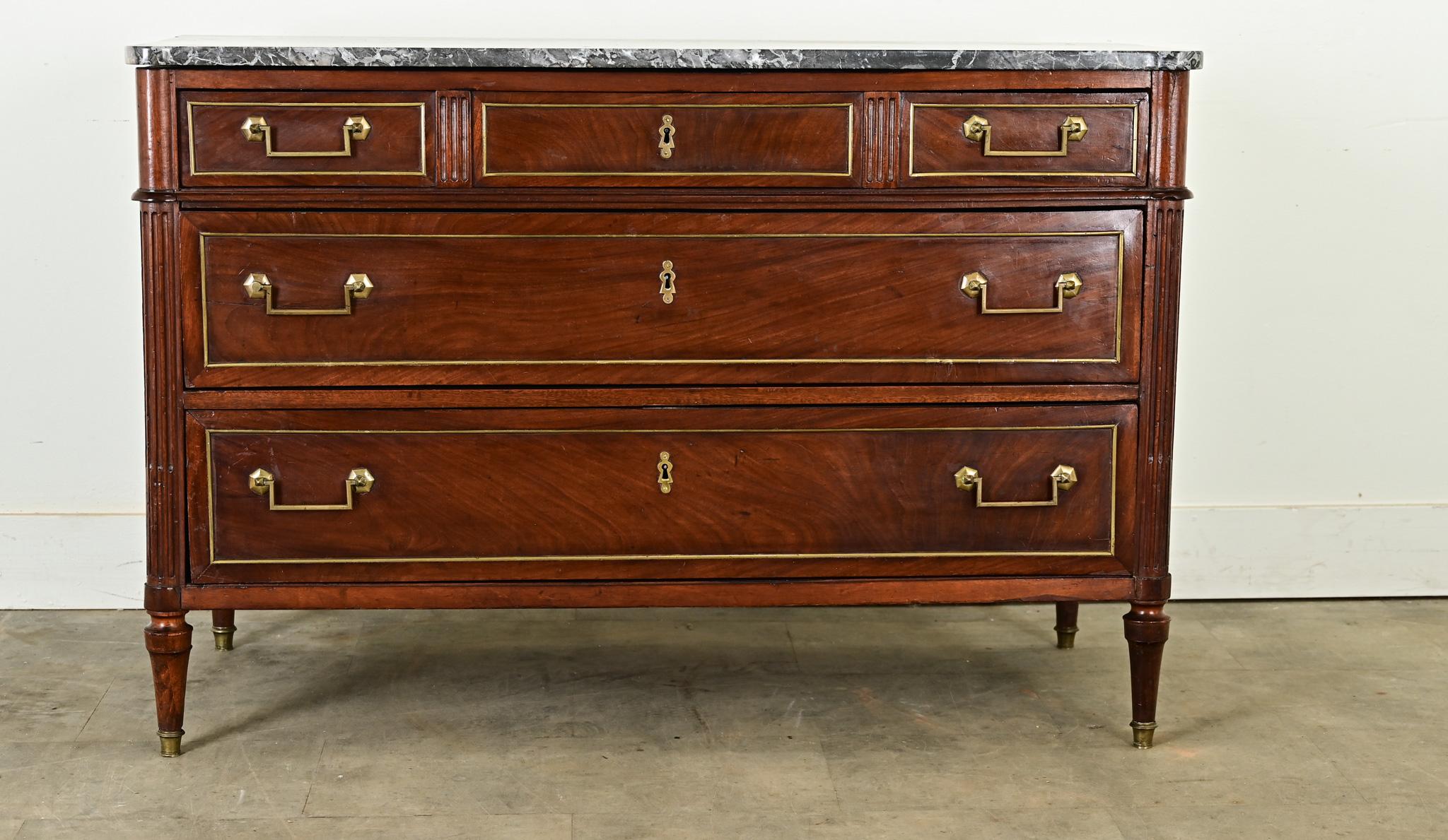A gorgeous Louis XVI style marble-topped mahogany commode from France, circa 1870, with Neoclassical and transitional details that could suit a wide range of decorating tastes today. The Saint Anne marble top exhibits striking patterns of dark grey