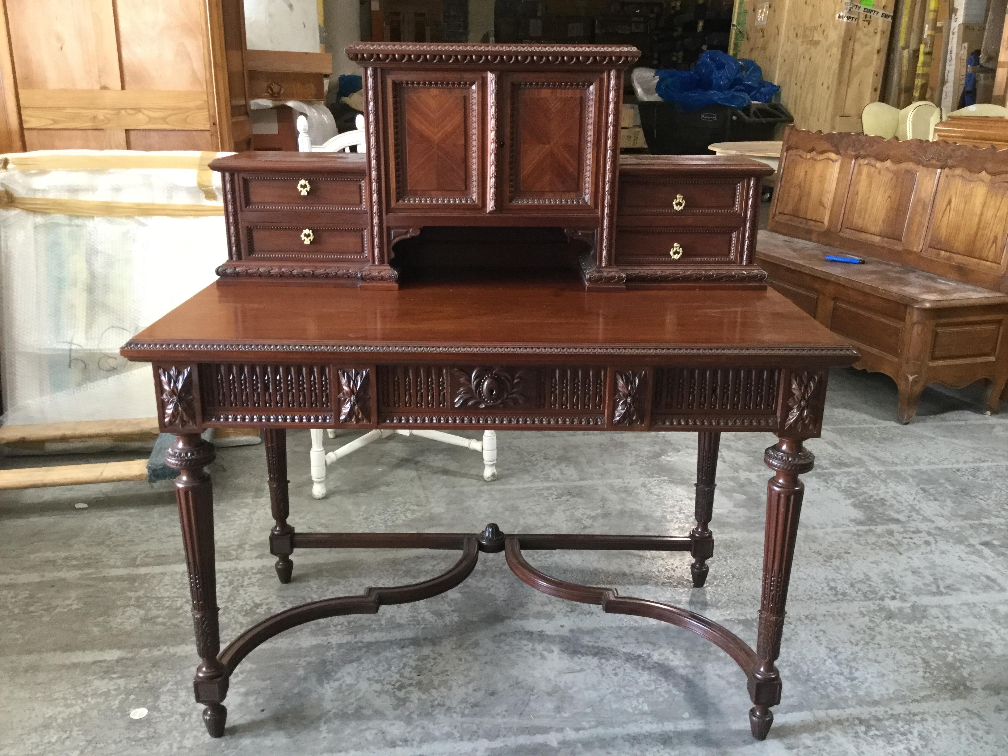 Stunning 19th century Louis XVI style writing desk. Made of solid mahogany, this piece features a flat work space and a top shelf which provides 4 small drawers and a central cabinet for additional storage. The beauty of this piece is in the refined