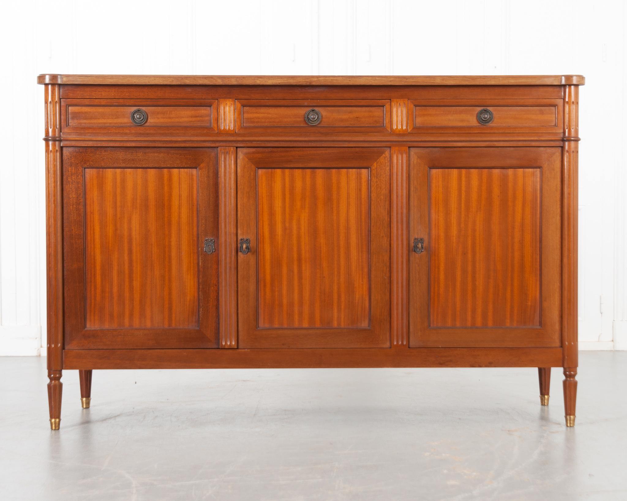 This French enfilade was crafted in the 1940's in the style of Louis XVI. A wonderfully patinated mahogany top with tureted corners that continue to the body as fluted pilasters. The apron houses three paneled drawers with matching drop ring brass