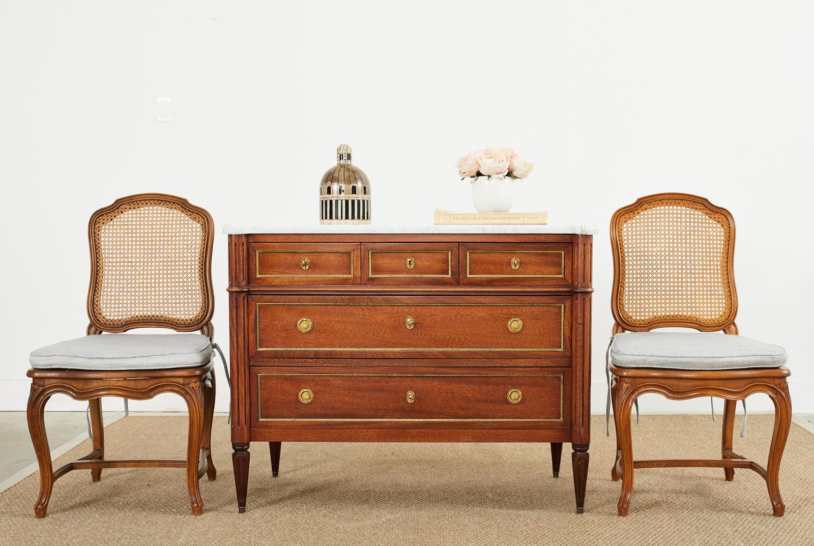 Dashing French mahogany marble top dresser, chest of drawers, or commode crafted in the grand Louis XVI taste. The three drawer chest has a mahogany case with reeded pilaster columns on the front corners and is topped with a conforming slab of