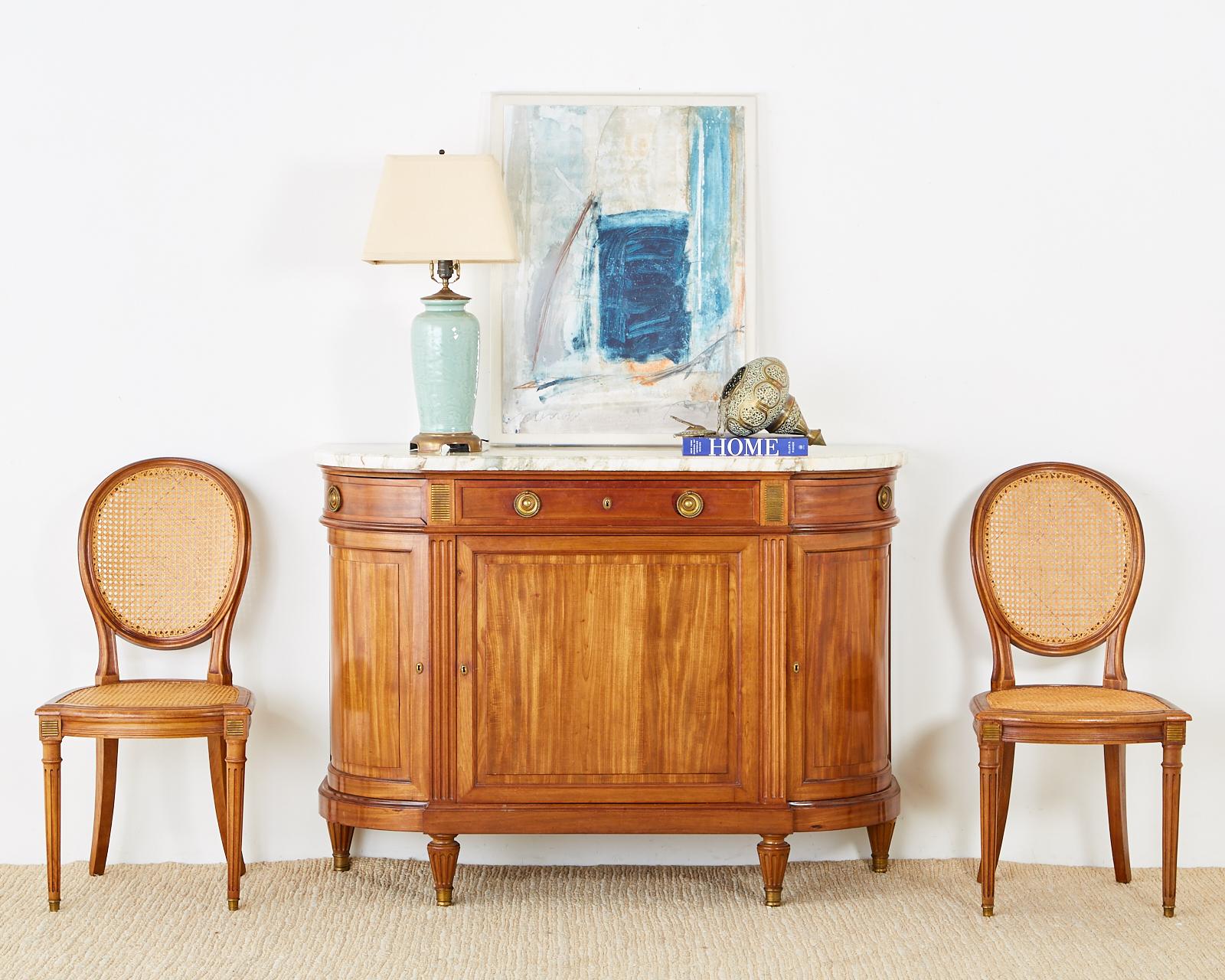 Distinctive French radiant mahogany sideboard server or buffet featuring a large Carrara marble top. Made in the Louis XVI or Directoire taste with neoclassical bronze mounted designs between the three top storage drawers. The case is crafted with