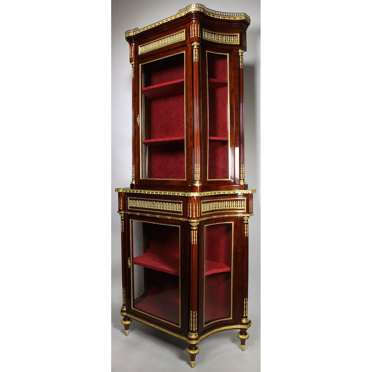 A fine French 19th century Louis XVI style mahogany and ormolu mounted two-tier vitrine cabinet. The upper section with a single glass front door below a pierced gilt-bronze floral railing and bowed glass side panels, the top with a draped gallery