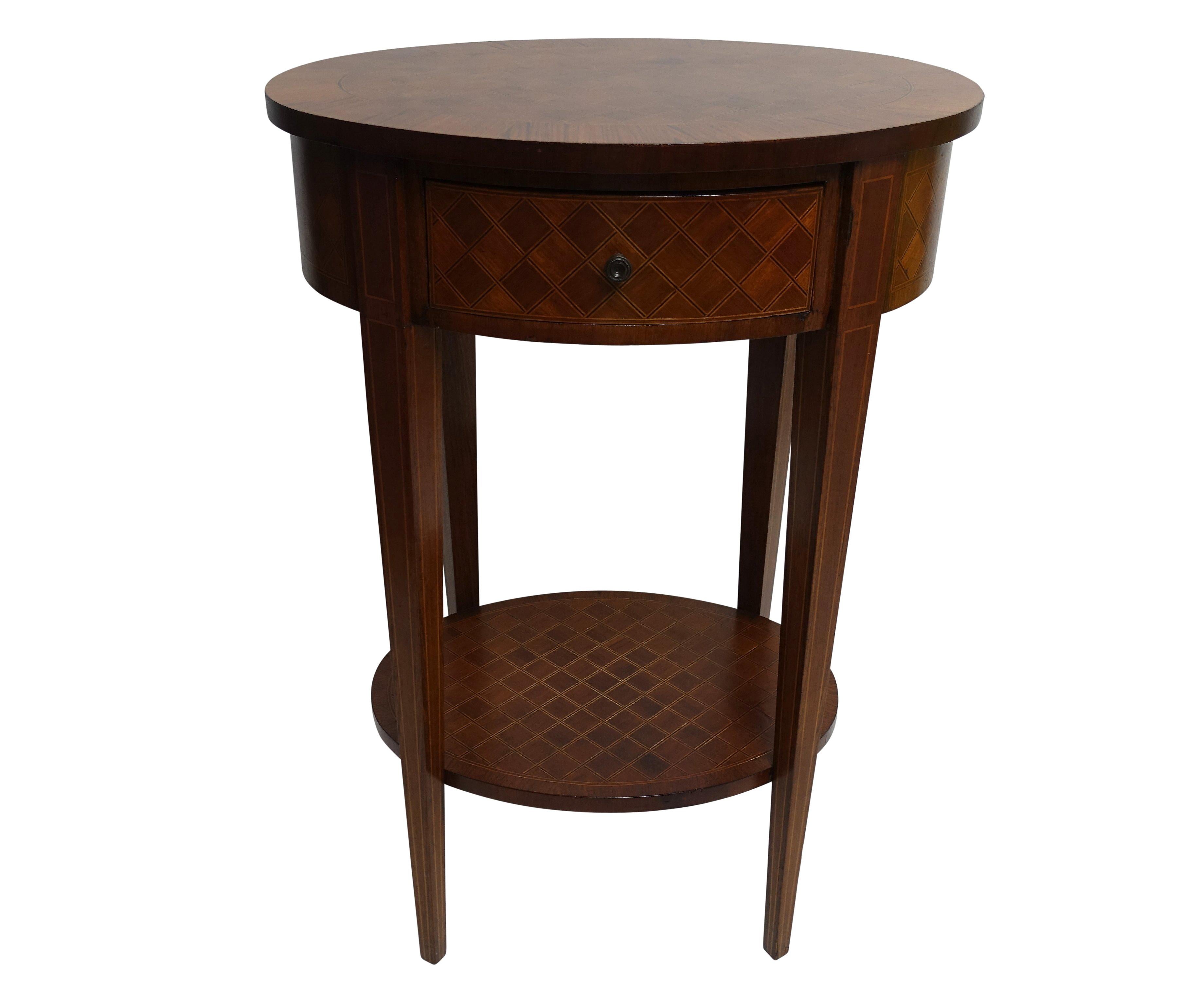 A Louis XVI style oval shape mahogany parquetry side table with satinwood and ebony inlay and a mahogany crossbanding border. Having a single drawer and a lower shelf.