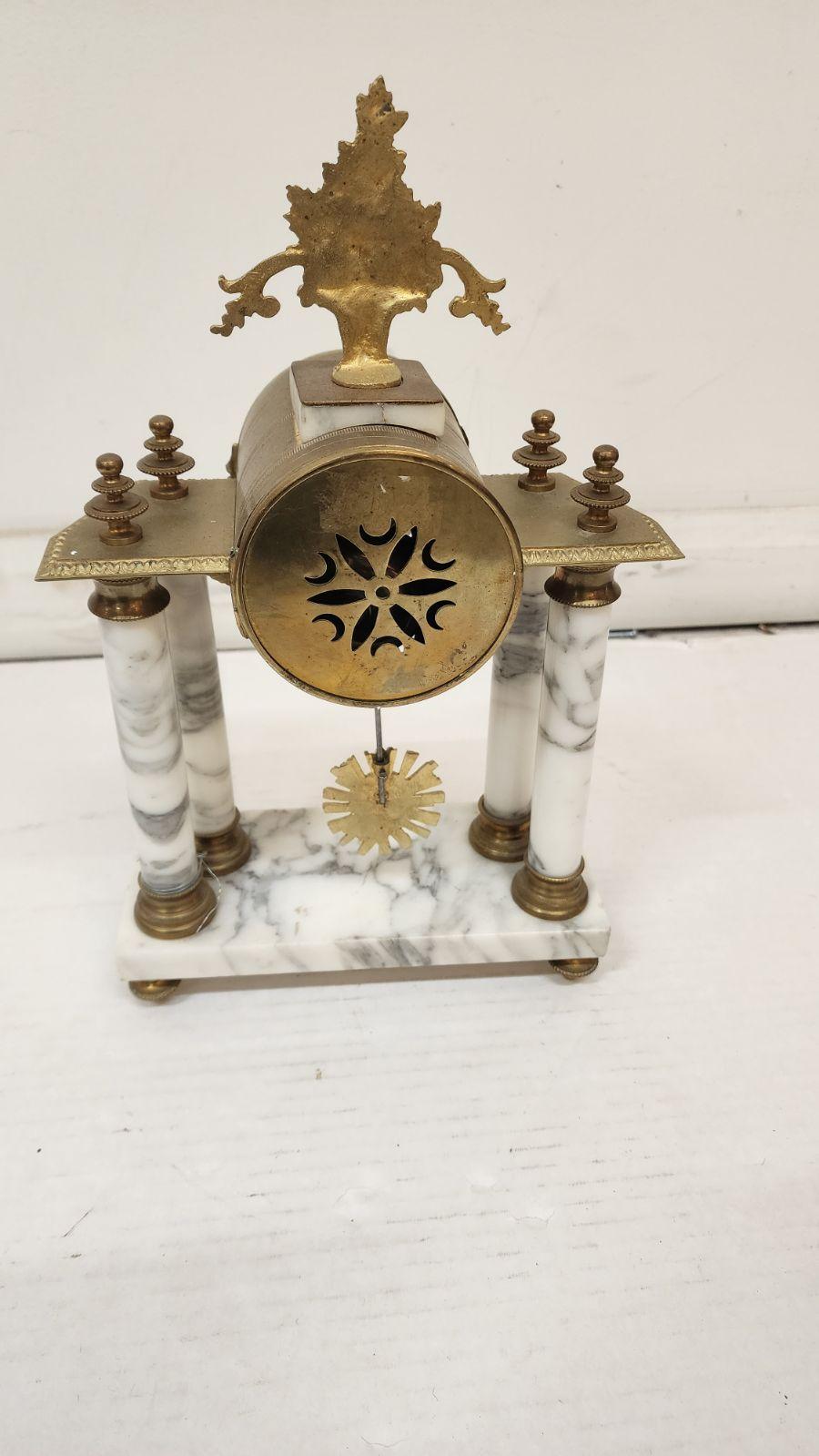 French Louis XVI style marble mantel clock, late 19th century; marble columns above the platform base, on toupie feet; gilt metal finial shaped like a basket of flowers; enamel fancy dial with Arabic numbers. 