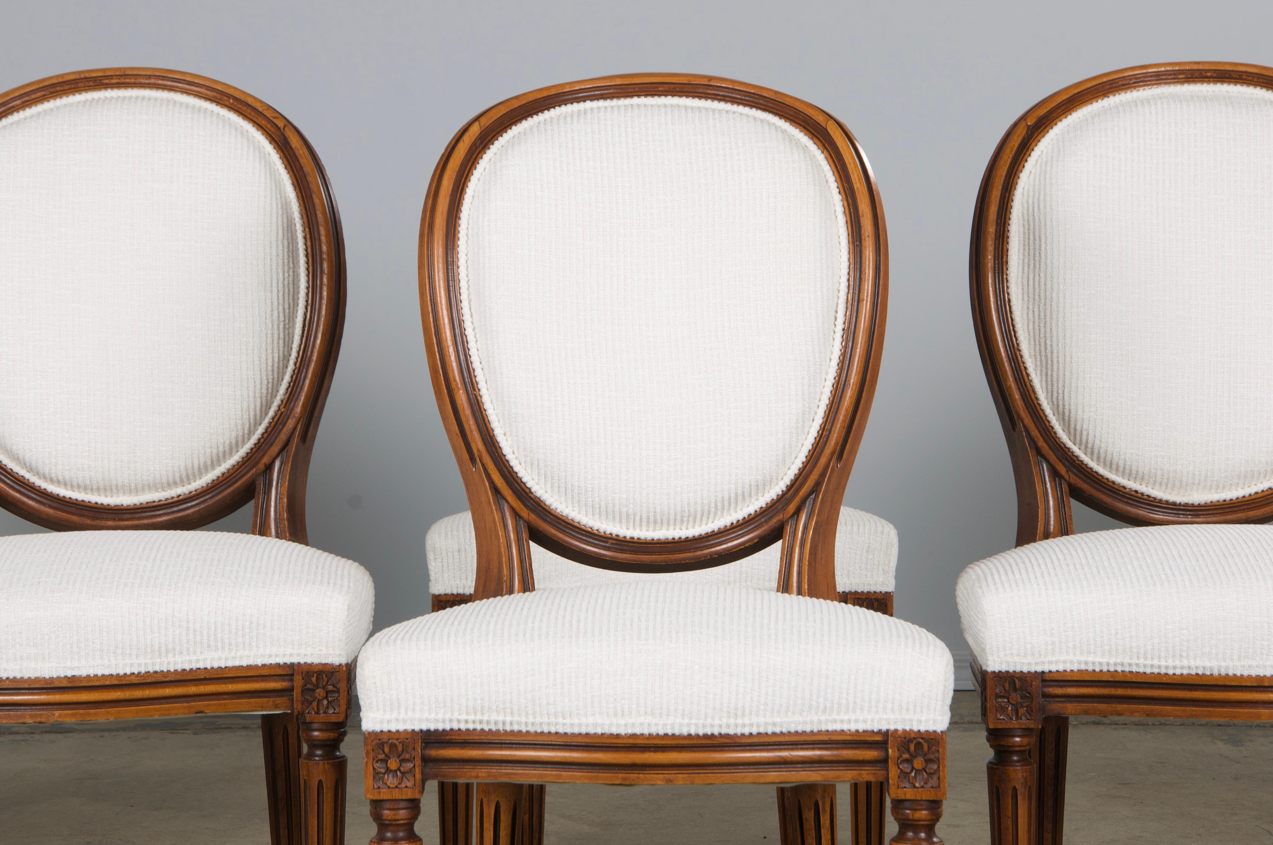 Un elegante set di sei sedie da pranzo francesi in stile Luigi XVI, provenienti dalla Provenza. Ogni sedia presenta una struttura in legno d'acero lavorata a mano con uno schienale a medaglione ovale. Due sedie sono leggermente più grandi e vengono