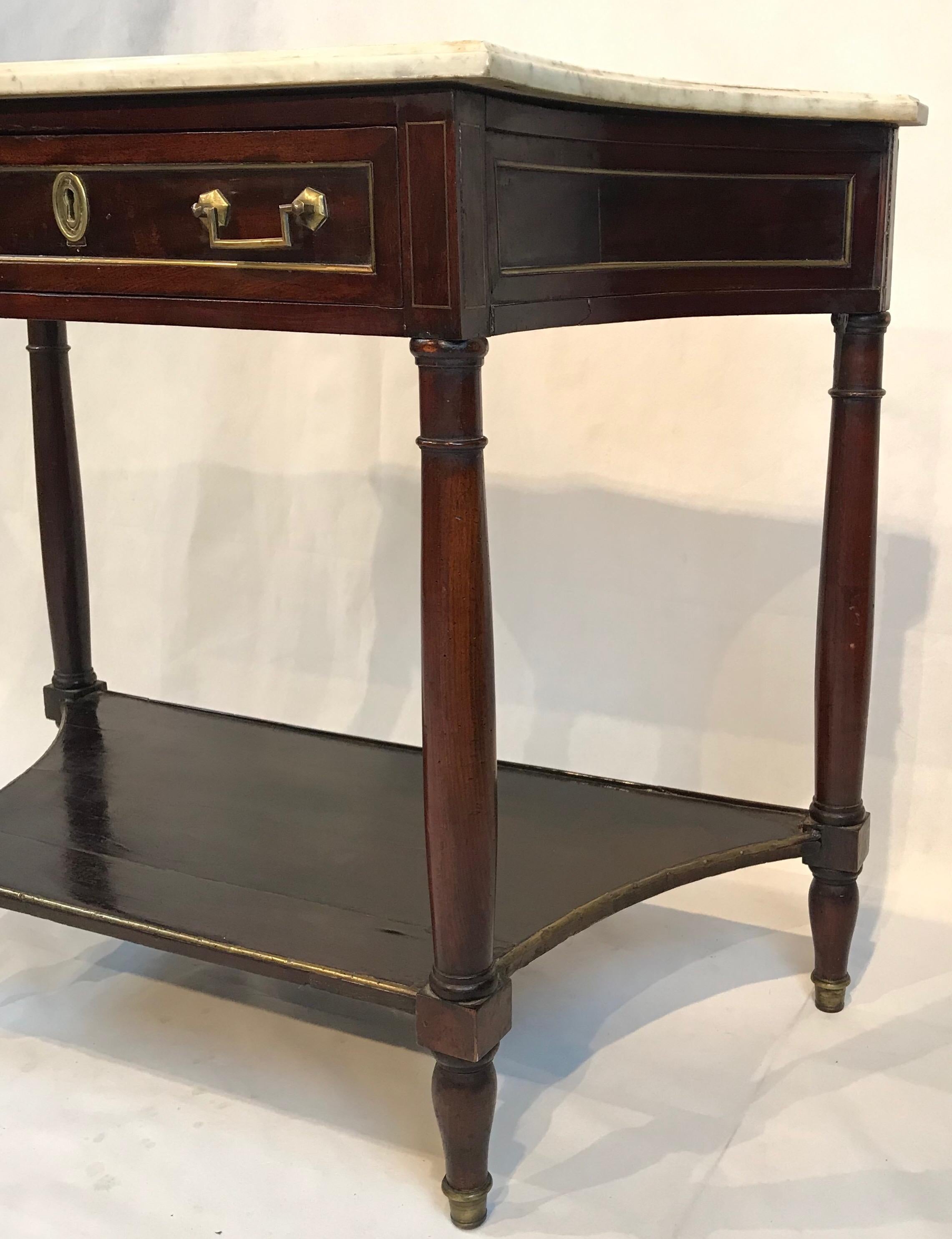 Beautiful mahogany console table having white marble top, bottom wooden shelf and single drawer. The decorative gold banding, pulls and escutcheon top off the stately piece.