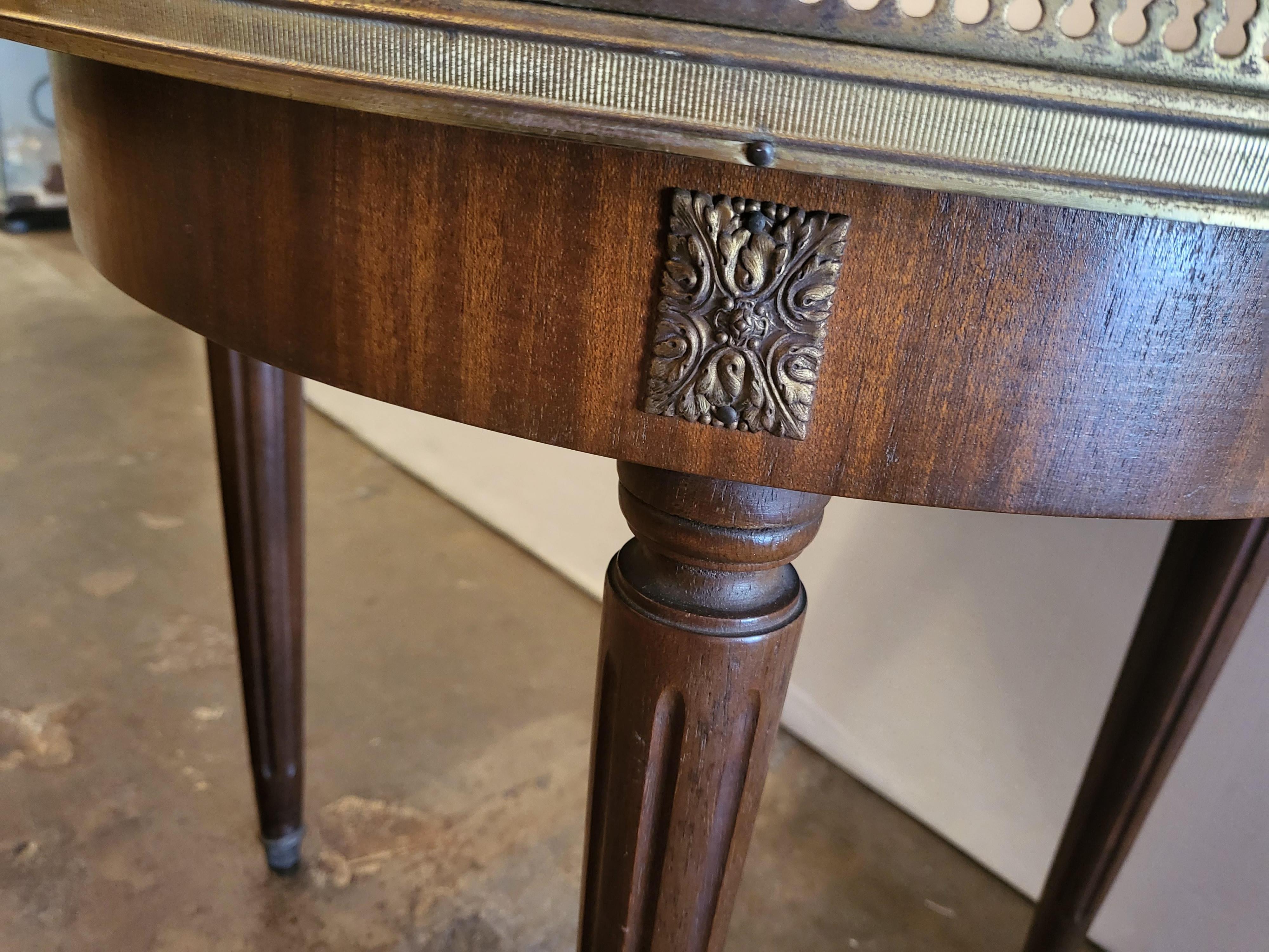 French Louis XVI style bouillotte type table, 20th c., pierced brass gallery enclosing the marble top, mahogany frame, rising on tapered fluted legs.