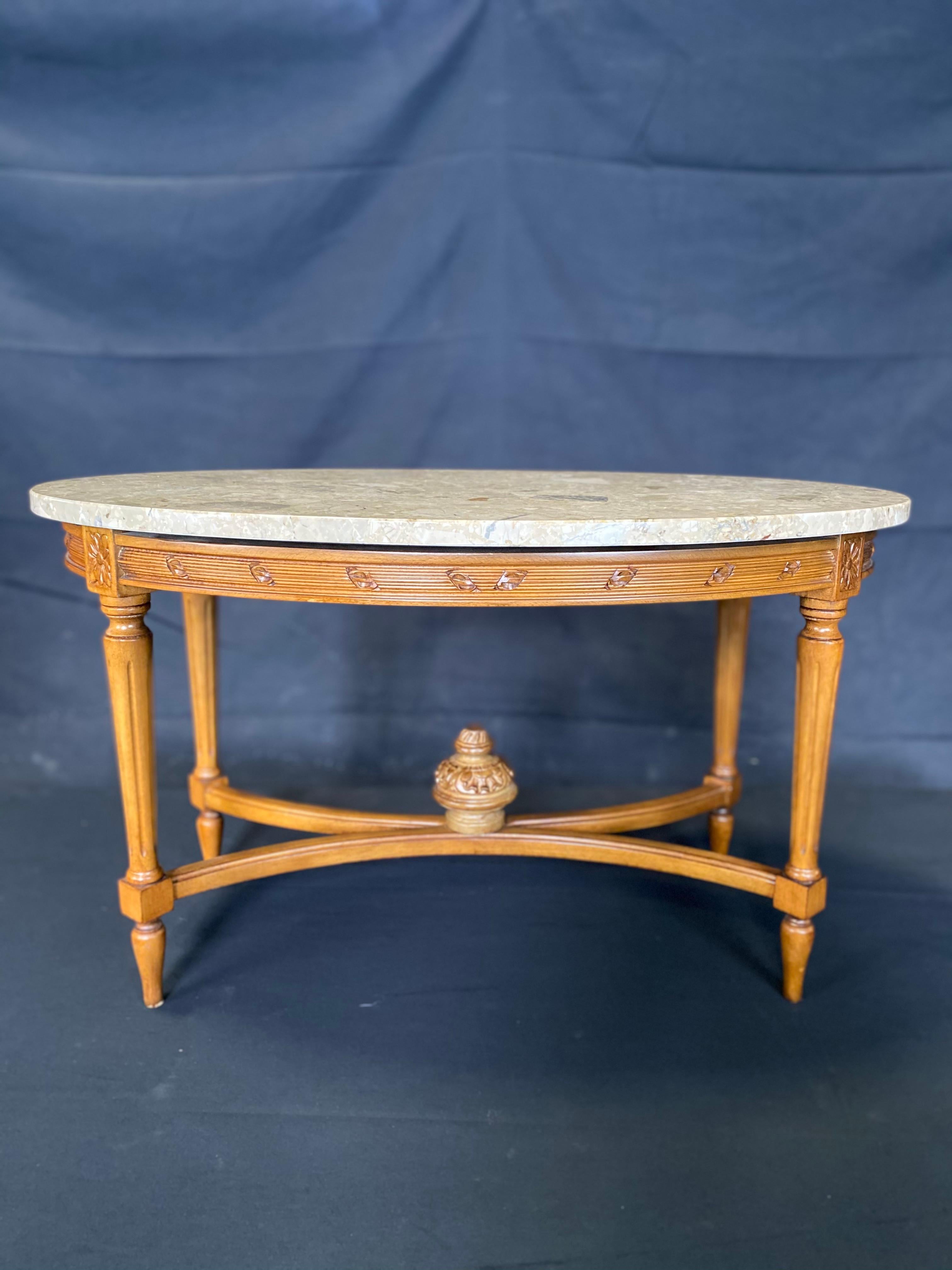 French Louis XVI style oval marble top coffee table, perfect size, with beautifully carved floret and reeding in the base. Great neutral beige marble top color. #5047.