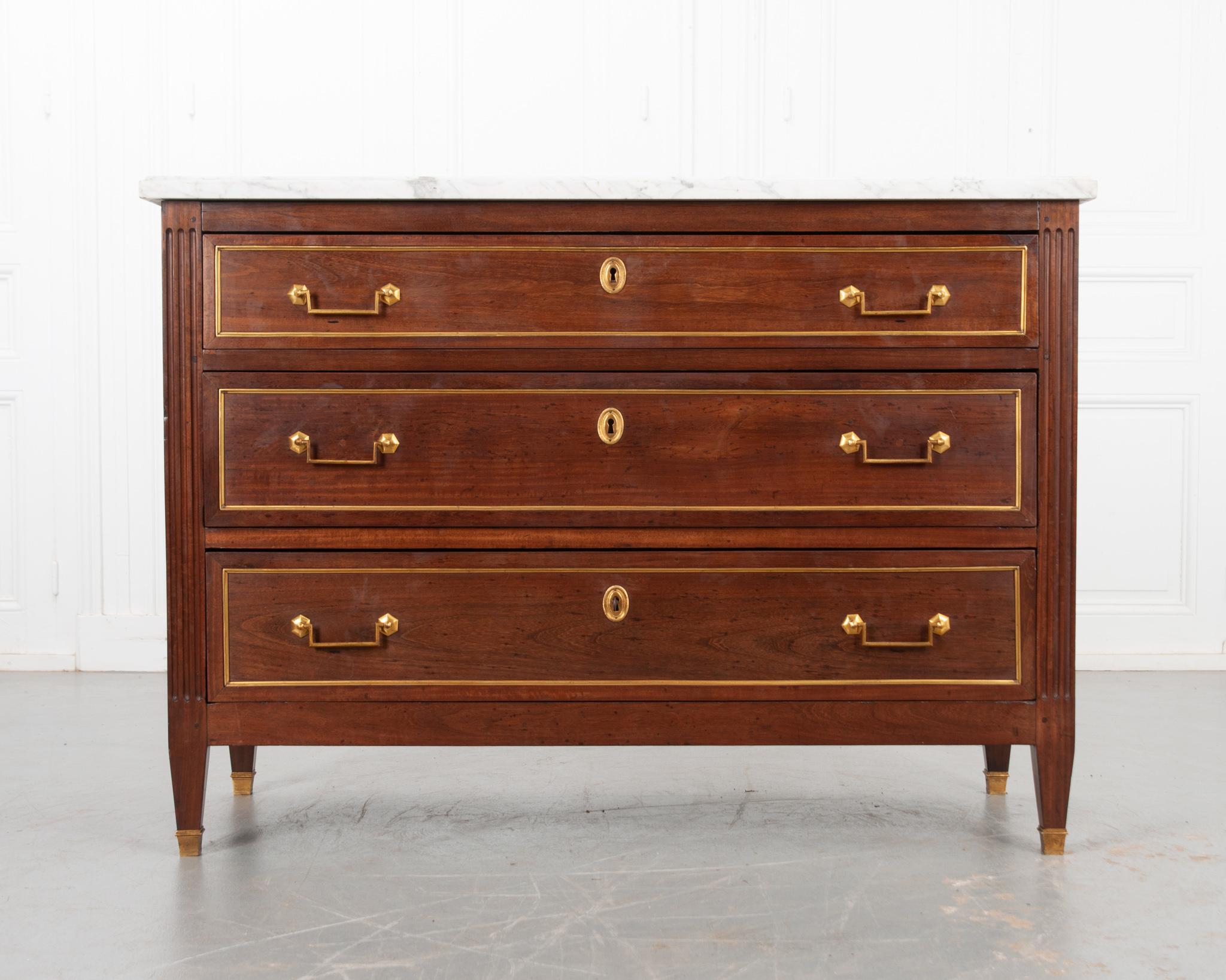 A wonderful Louis XVI style commode from 19th century France. Mahogany body topped with its original piece of  white marble featuring an ogee edge. Fluted details flank three wide drawers which have all been cleaned and easily open. Each paneled