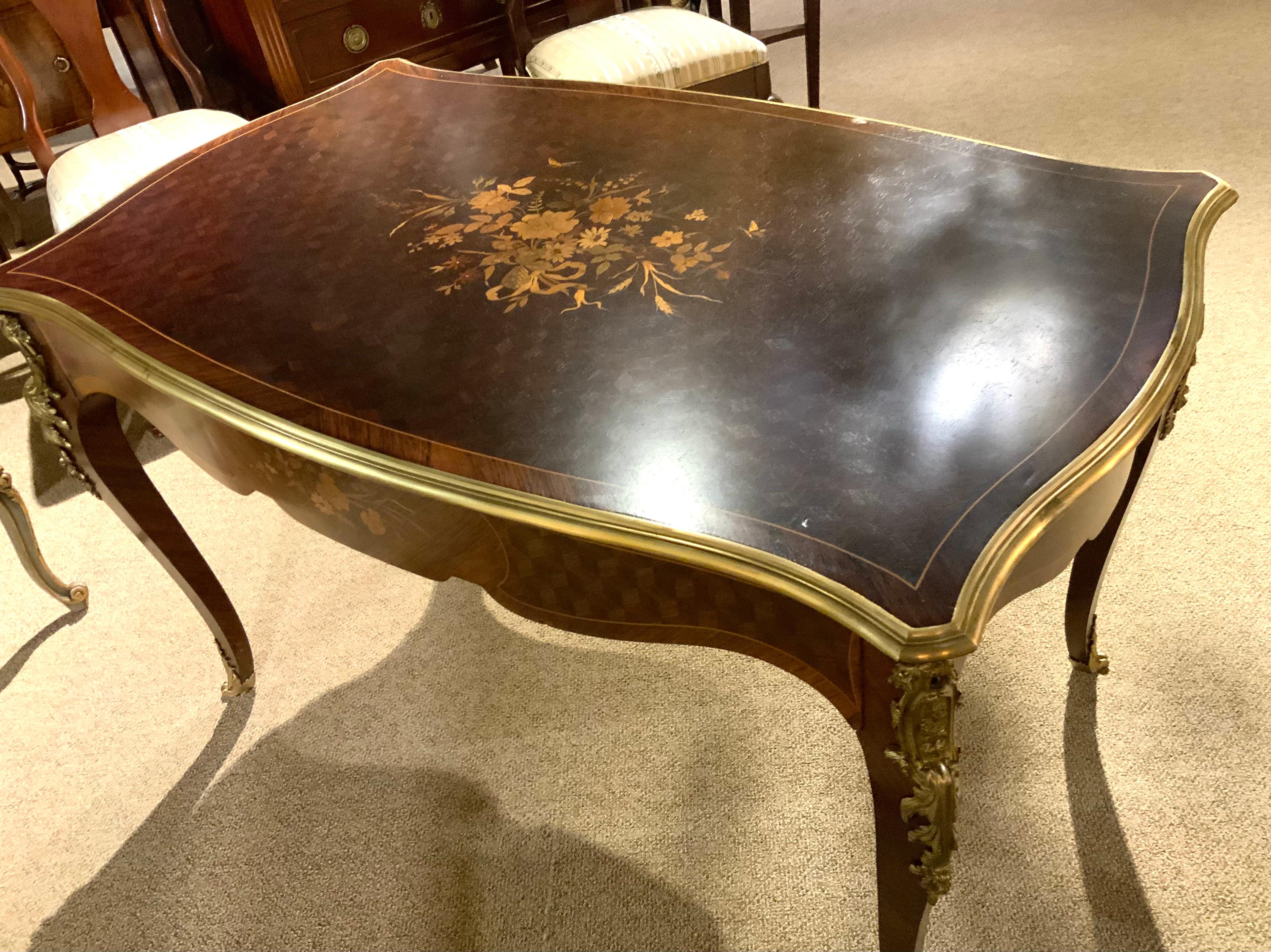 The exquisite shape of this desk makes it especially desirable. The 
Marquetry inlay in a floral motif is centered on all sides in several
Exotic woods. The bronze dore mounts are well cast and the patina
Is in original and bright patina. It has