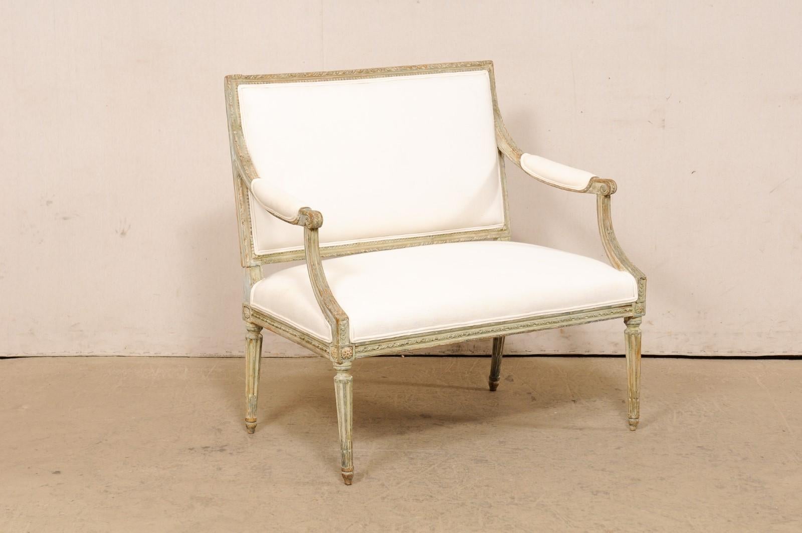 A French Louis XVI style carved-wood and upholstered marquise from the 19th century. This antique chair-and-a-half from France, often referred to as a marquise (a wide fauteuils chair), showcases all the Louis XVI decorative vocabulary with tightly