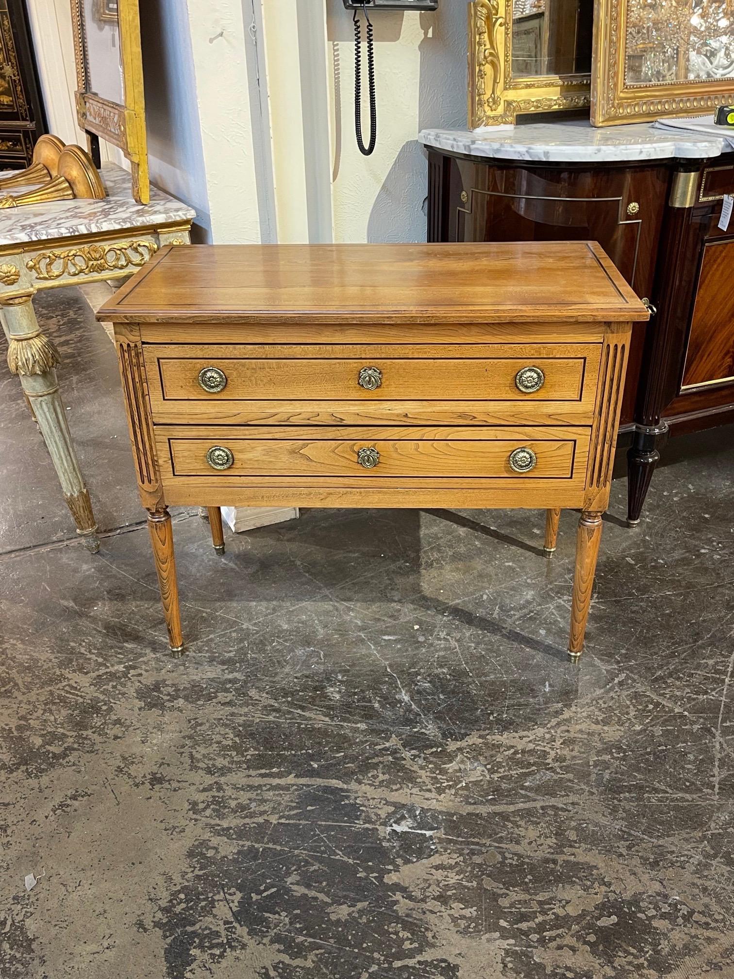 Belle commode française de style Louis XVI en chêne avec garniture en laiton. Des lignes épurées et deux tiroirs pour le rangement. Cette pièce s'intègre bien dans une variété de décors !