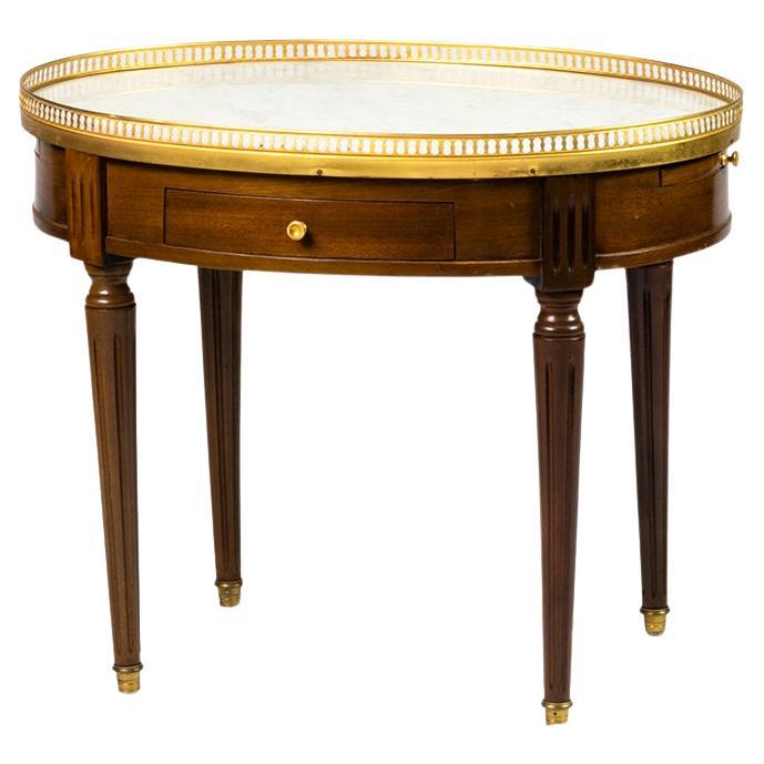 This French Bouillotte table, crafted in the 19th century, is a refined example of Louis XVI style furniture. 
Its oval form is topped with a white marble surface, encircled by a delicate gilt bronze gallery rail, characteristic of the period.

The