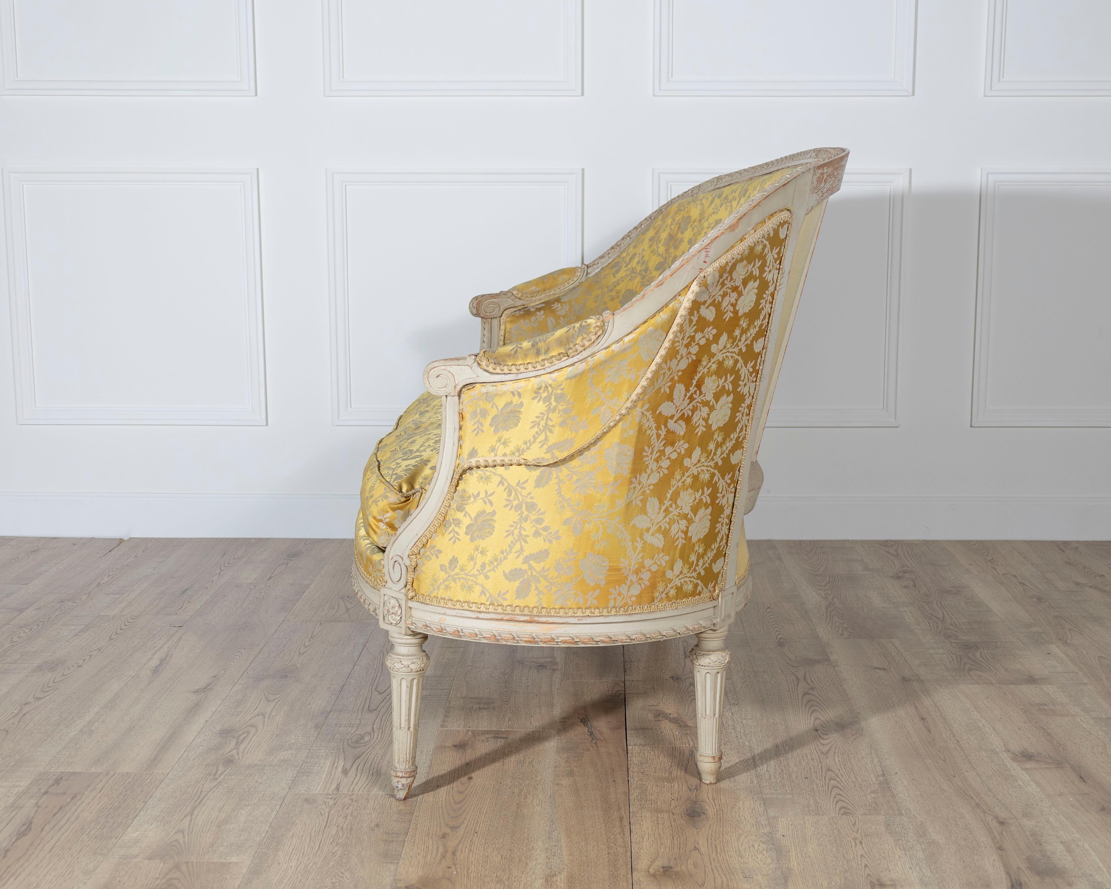 Un bellissimo e raffinato canapè francese in stile Luigi XVI, risalente al XX secolo, caratterizzato da un'elegante cornice intagliata e dipinta e rivestito in un vivace damasco floreale giallo. La forma curva dello schienale a botte crea