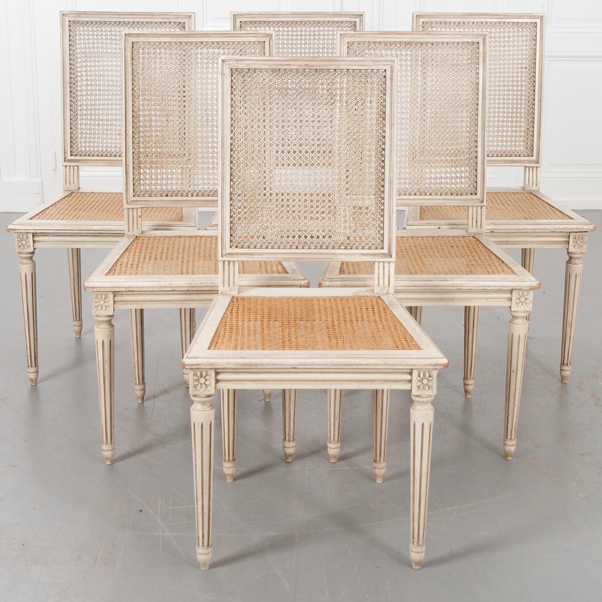A set of six Louis XVI-style painted cane dining chairs. The seats are more recent and are in great condition. The chairs feature simple lines with fluted legs. The height of the seat is 17-½”.