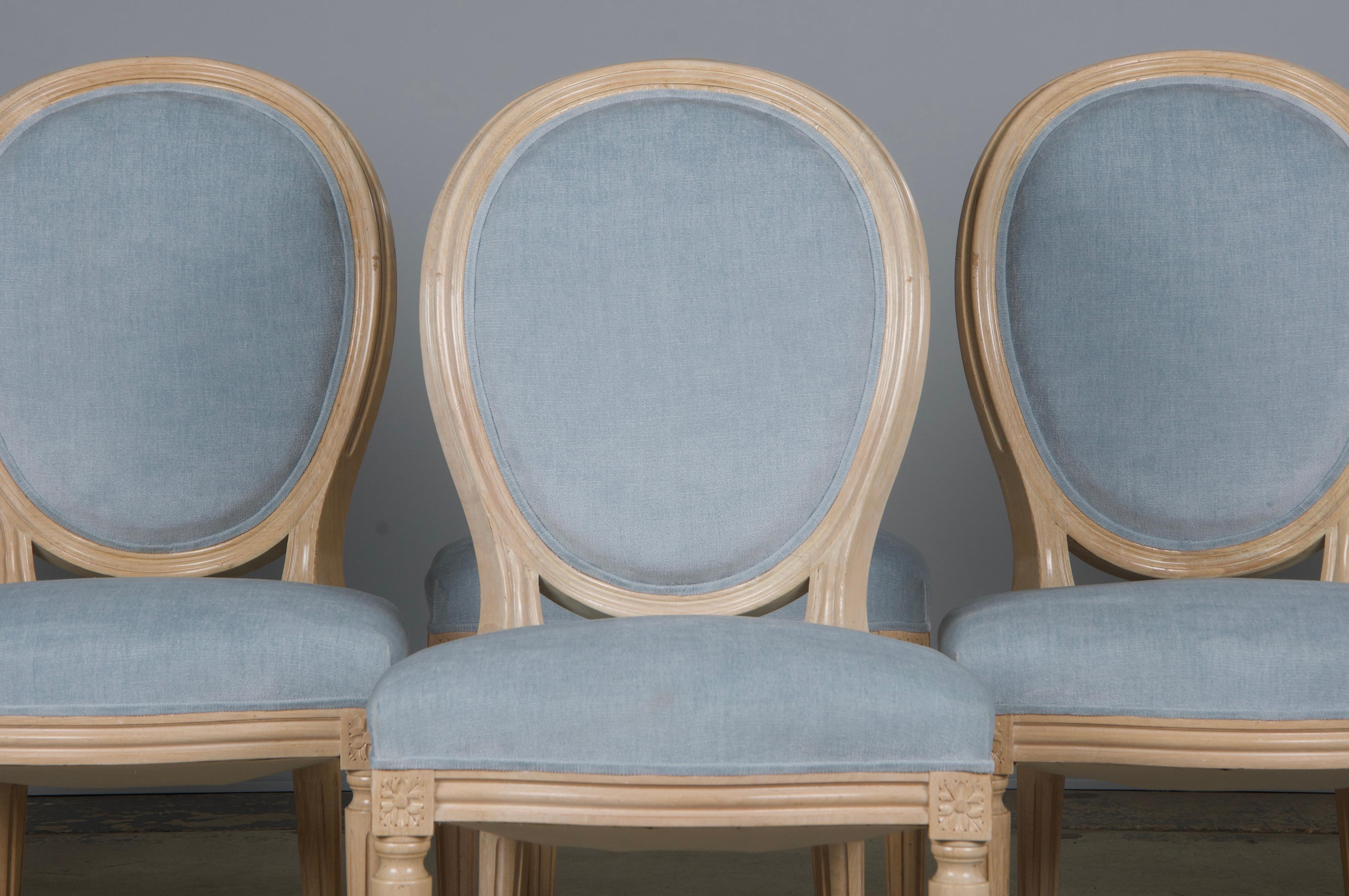 An elegant set of six French dining chairs in the Louis XVI style, sourced from Provence, France. Each chair features a hand-molded frame with a refined oval medallion back, finished in a creamy antique white with a naturally aged patina and subtle