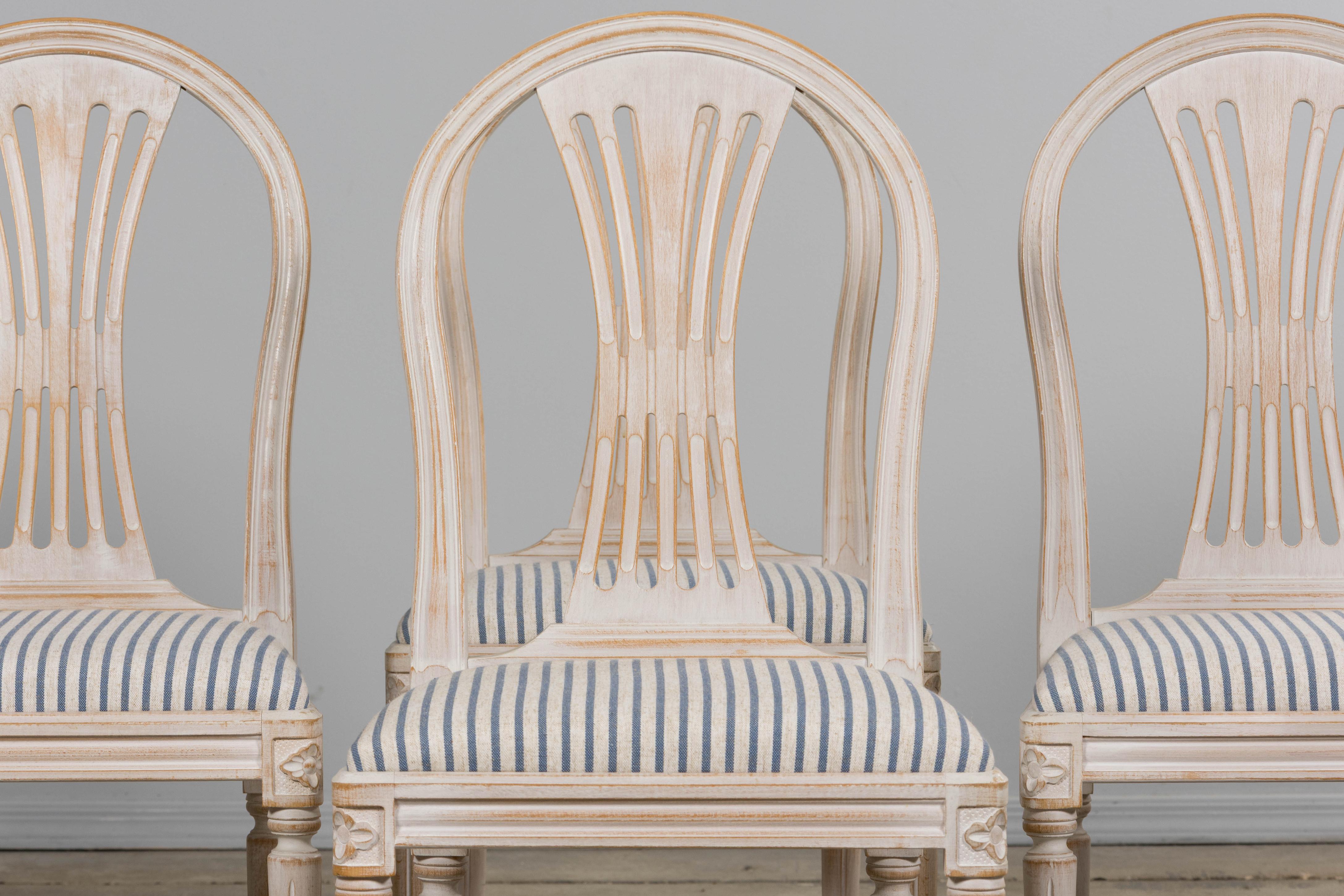 An elegant set of six mid 20th century French Louis XVI style dining chairs, sourced in Provence. Each chair presents an arched shield-back with a pierced splat, over a carved seat rail with rosettes at the corners, raised on tapered, fluted legs