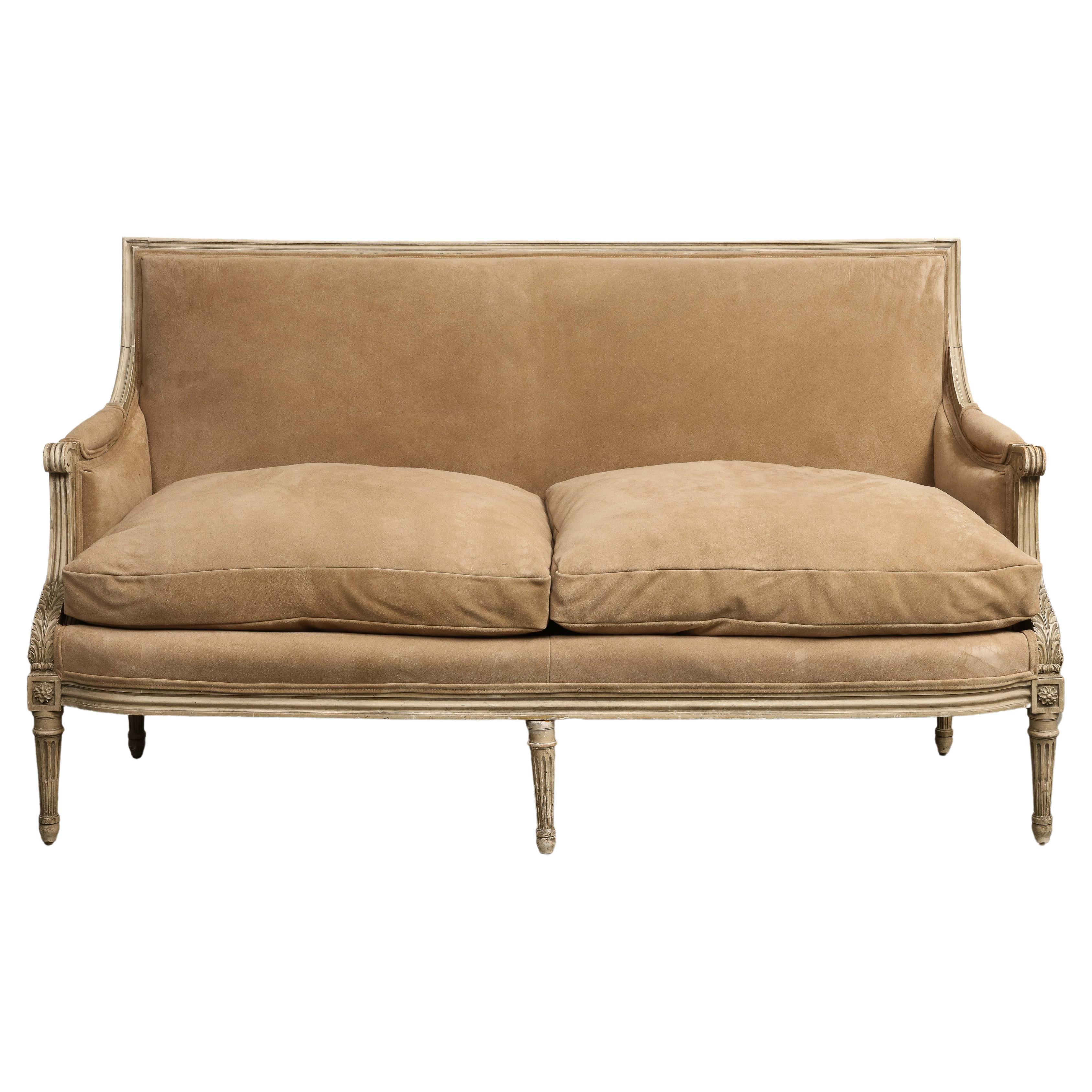 French Louis XVI Style Painted Settee, circa 1930, with beautifully carved arm details and fluted tapered legs. 

Reupholstered in 2023 in Edelman Royal Suede - Paper Bag

Additional dimensions: 
Seat Height 22