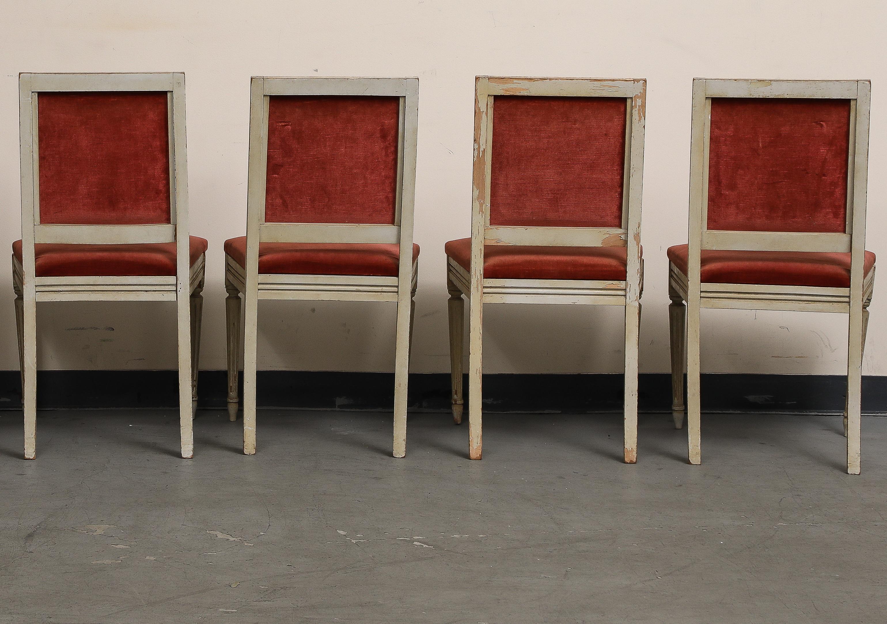 Ensemble de quatre (4) chaises d'appoint peintes de style Louis XVI, datant du début du 20e siècle. Peinture d'origine / finition déformée sur les cadres avec des pieds cannelés et effilés. L'assise et le dossier sont recouverts de velours rouge