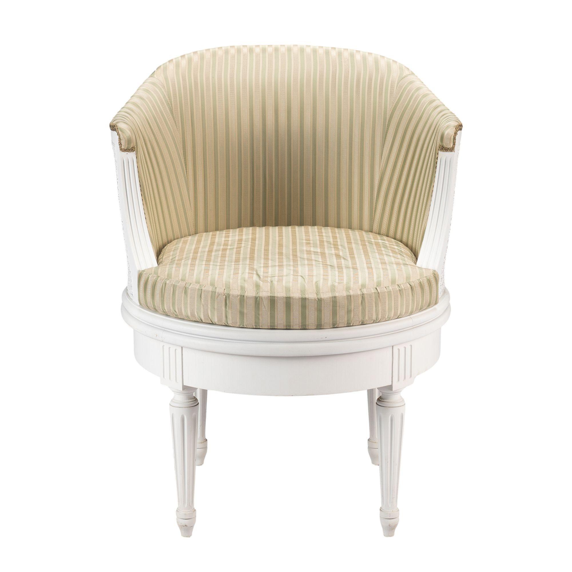 Fauteuil pivotant peint dans le goût Louis XVI. La chaise a un dossier intérieur tapissé avec une garniture de gimp et un cadre extérieur canné. Le siège est canné et équipé d'un coussin rembourré. L'assise est soutenue par quatre pieds tournés et