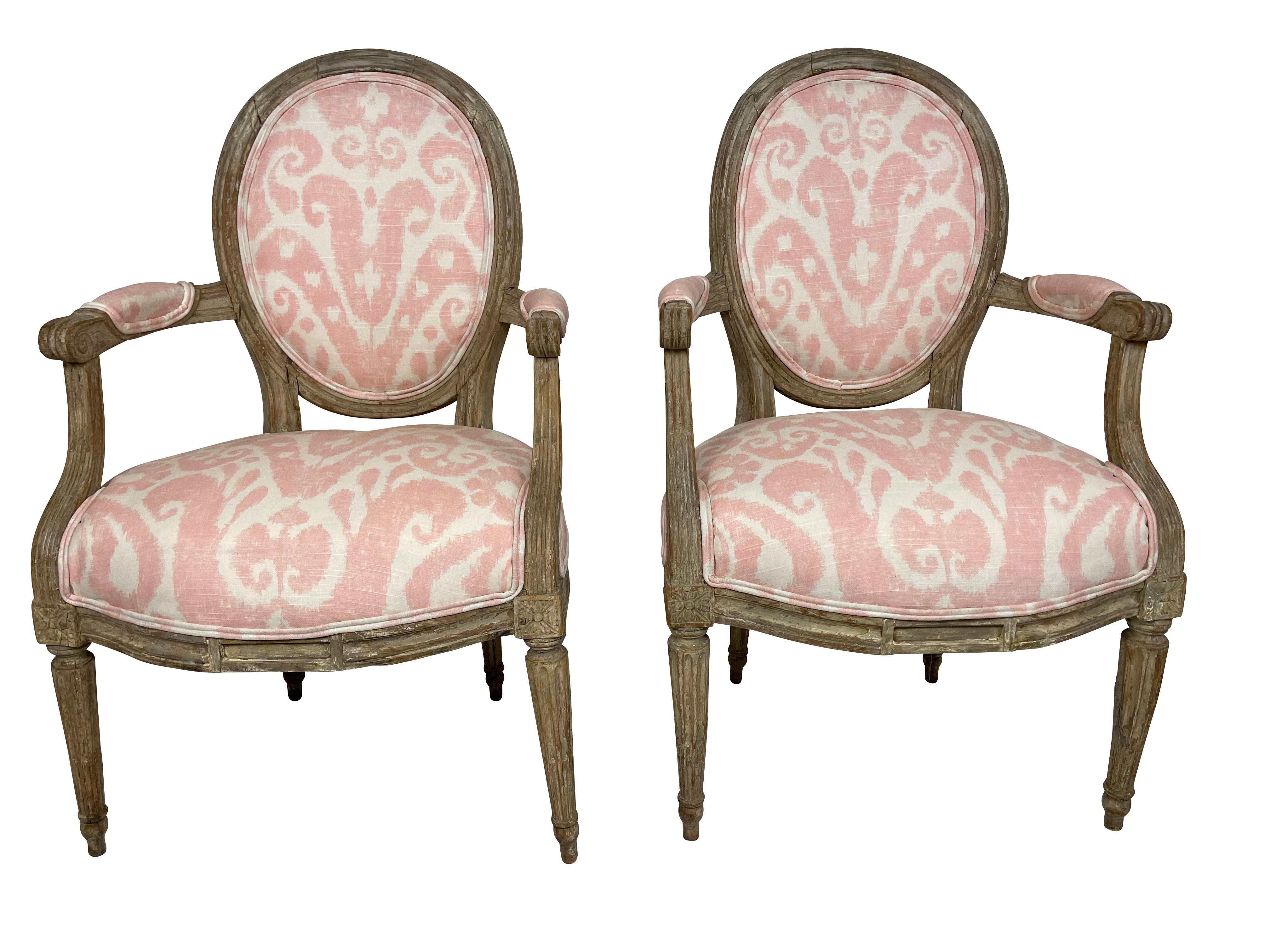 Pair of Grey painted and carved Louis XVI style small armchairs. Perfect for a little girls' room or bedroom. Newly professionally upholstered in pink Ikat fabric.