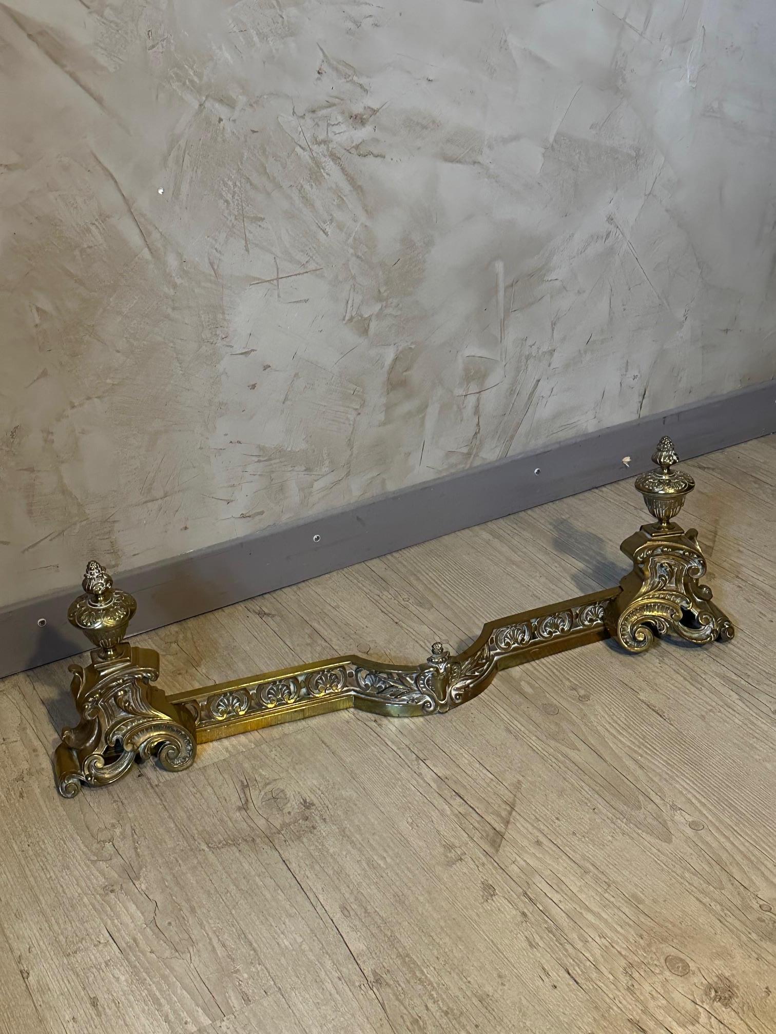 Nice pair of Louis XV style gilt bronze andirons with adjustable fender
The two andirons are detachable from the fender. The andirons are representing medicis. 
The andirons are used: To support the logs without them directly touching the floor of