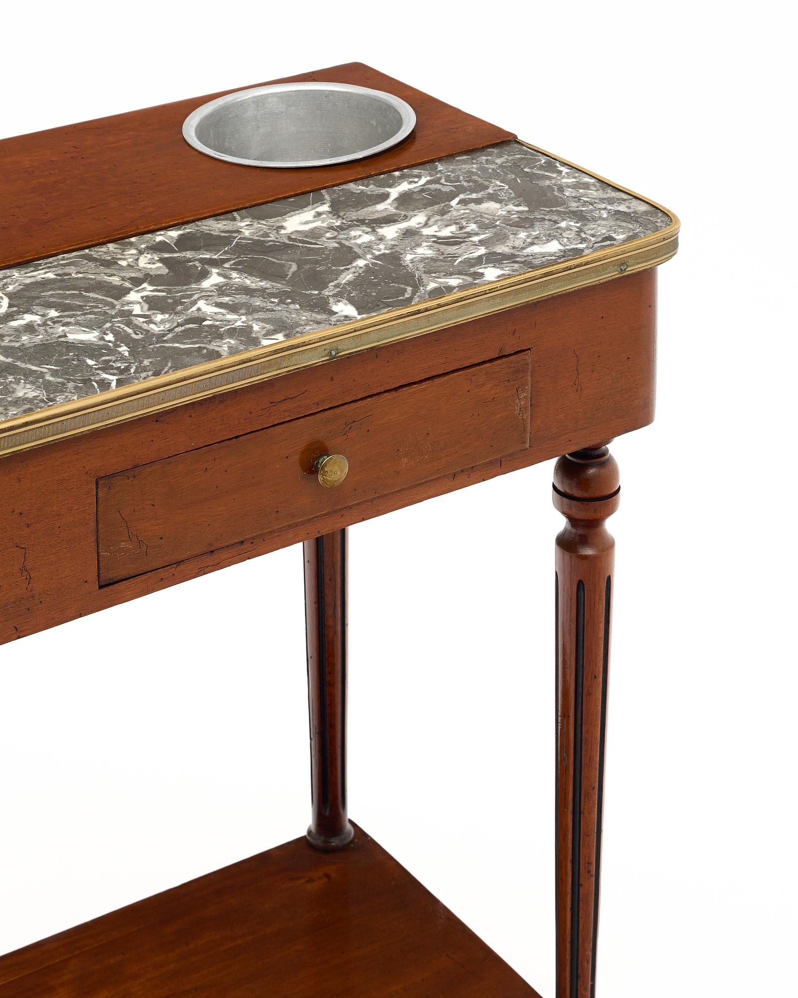 Table Rafraichissoir de France de style Louis XVI. Cette magnifique table d'appoint antique est dotée de deux porte-verres à champagne en métal et d'un petit tiroir pour les accessoires de bar. L'acajou a reçu une finition lustrée à la française. Il