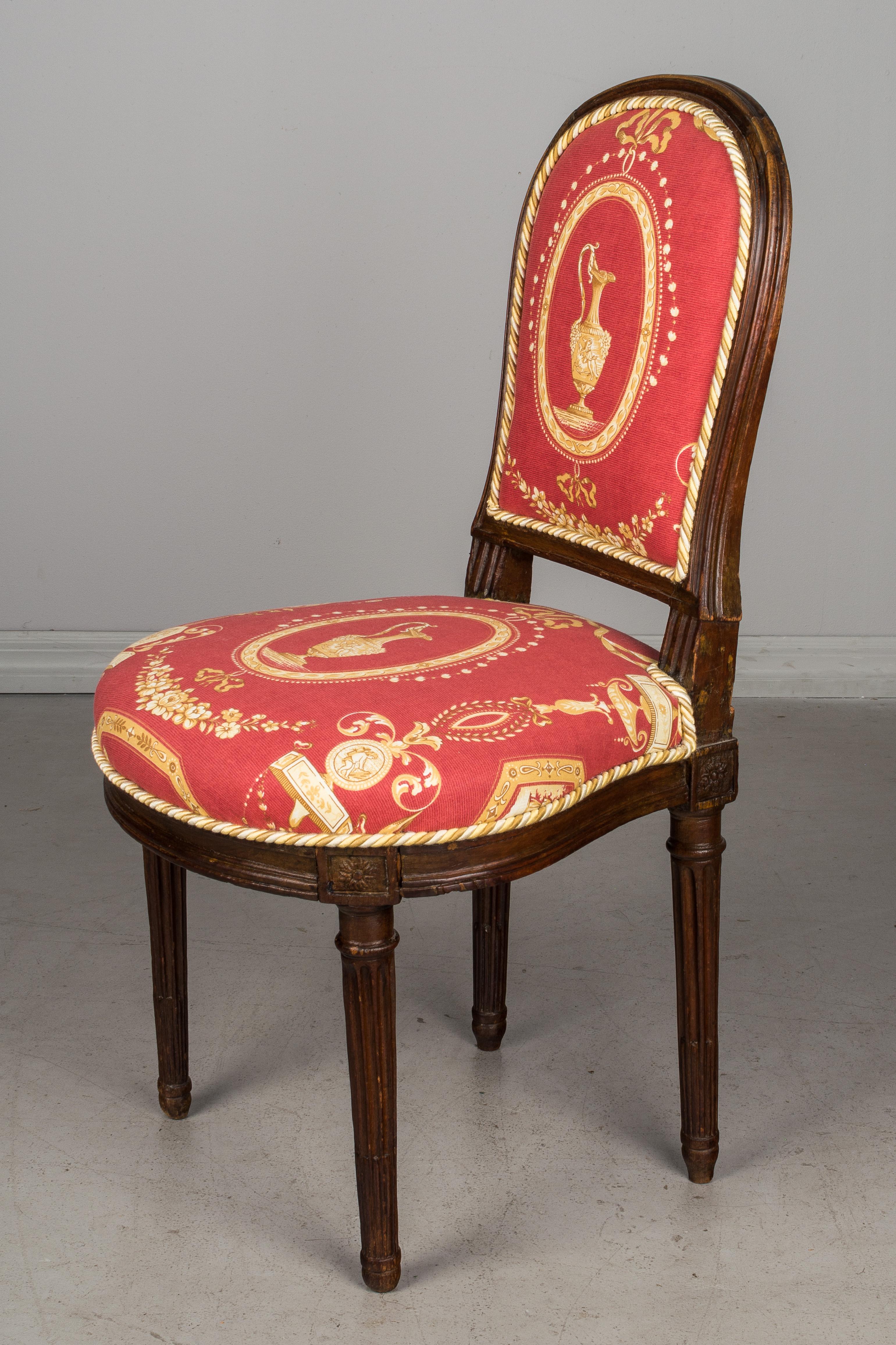 A 19th c. French Louis XVI style small parlor chair made of beechwood with carved details. Upholstered in a Fine decorator fabric with a custom cotton canvas slipcover. This petite side chair is a nice accent piece for a foyer and is sturdy for
