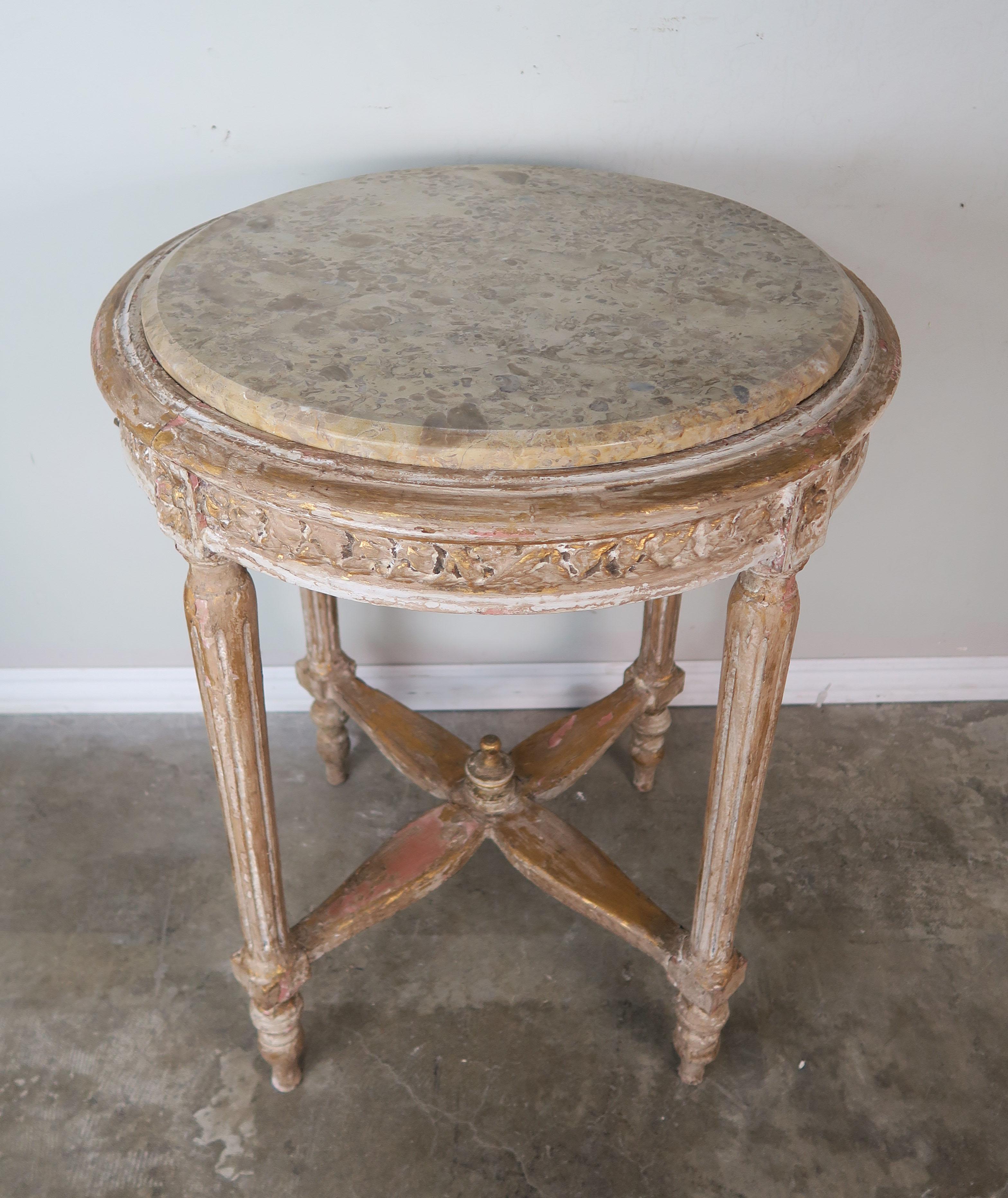 French Louis XVI style side table in a painted finish with gold leaf highlights throughout. The table stands on four straight fluted legs that meet together at a centre finial. Inset marble top in soft shades of gold, taupe and cream.