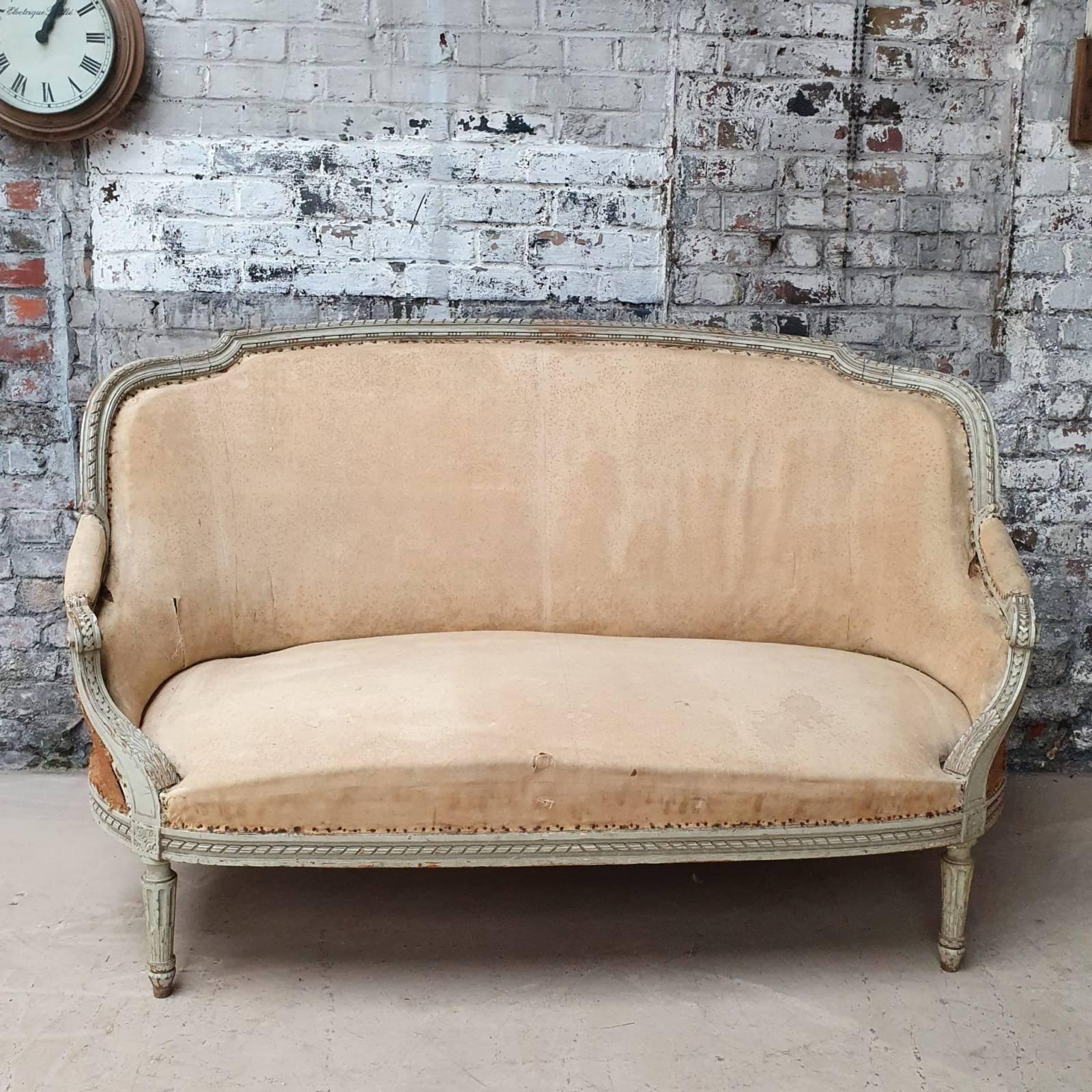 An exquisite French 19th century Louis XVI style sofa. Make a statement in your living space with this elegant sofa. Featuring the original patinated green/grey paint on a hand carved frame, this settee has been stripped down to the muslin and is