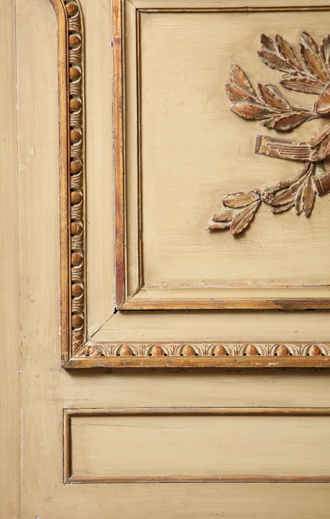 A French Louis XVI style trumeau mirror, beige painted frame with musical trophy carved applique within an egg and dart carved border, above a divided mirror plate.