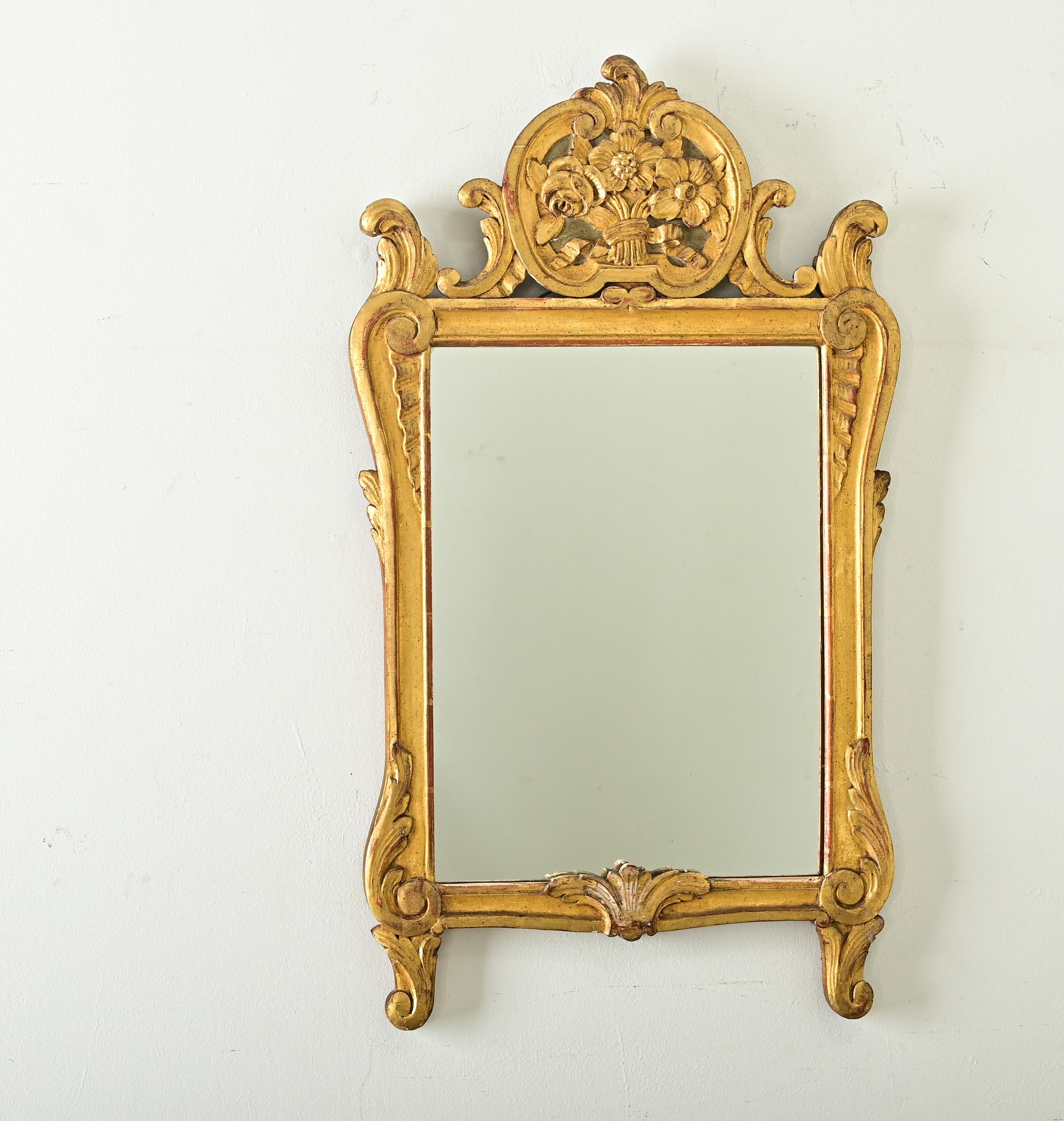 Magnifico specchio trumeau francese del XVIII secolo in stile Luigi XVI, gli intagli rococò sulla cornice in legno dorato appaiono ancora più animati sotto uno strato d'oro. Nella parte superiore del pezzo c'è un cartiglio quasi sferico - il fronton
