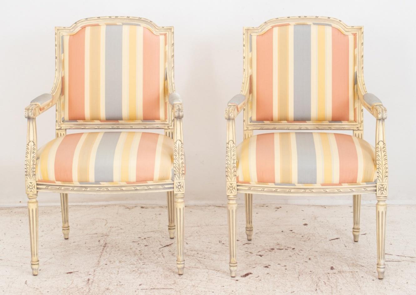 French Louis XVI style pair of painted white and lightly patinated arm chairs raised on turned tapered legs, upholstered with a light striped fabric.

Dimensions: 35.5